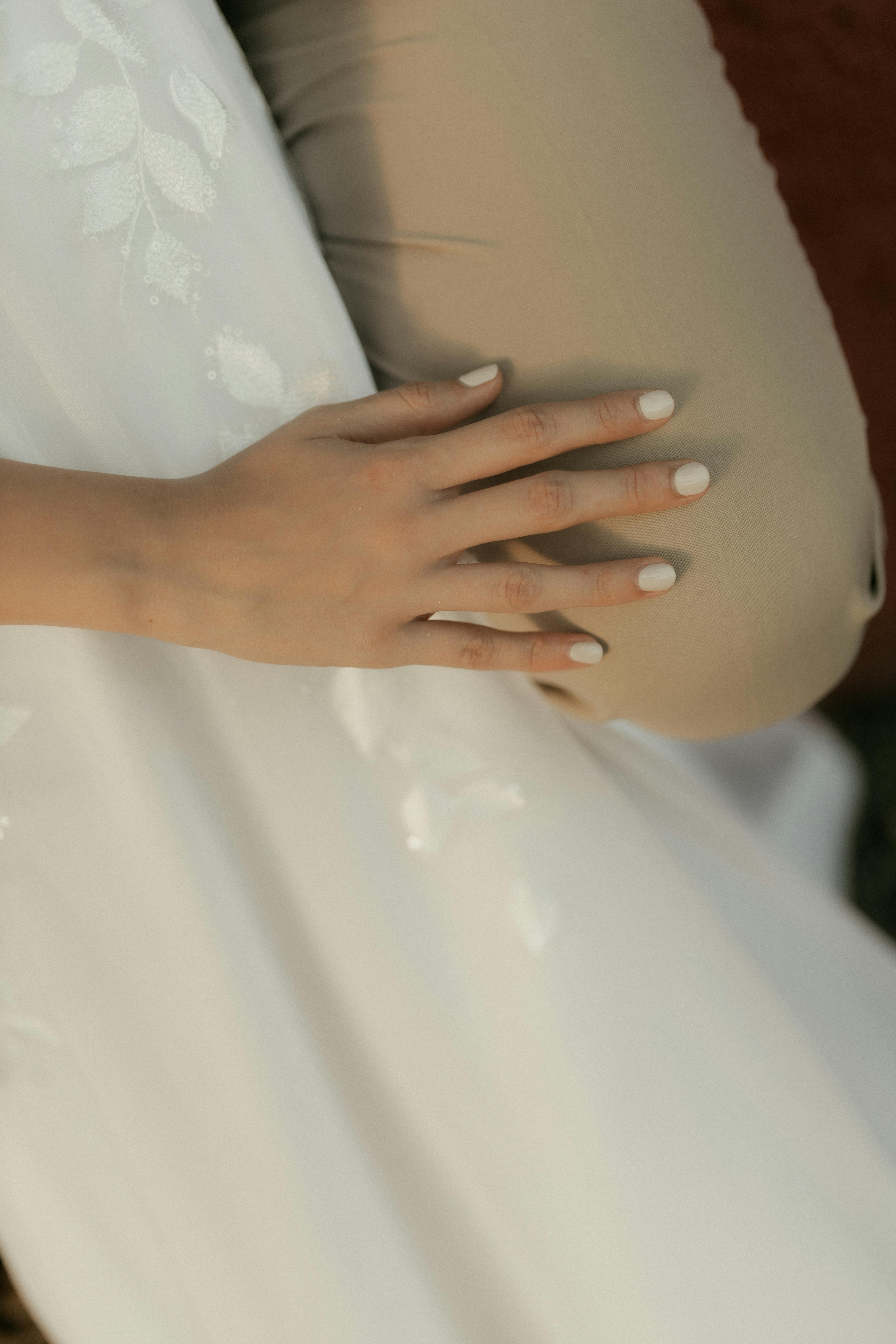 無料 ベージュの表面の上に置かれた、美しく手入れされた手のクローズアップ。穏やかで洗練された美しさを醸し出している。 写真素材