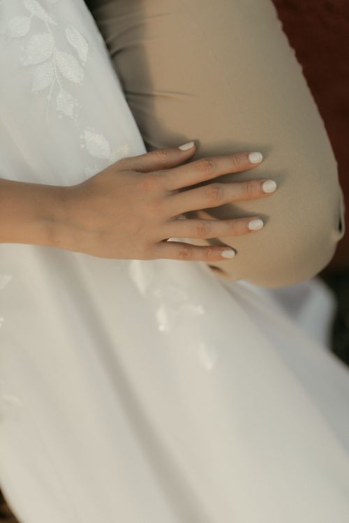 Free Close-up of an elegantly manicured hand resting on a beige surface, creating a serene and refined aesthetic. Stock Photo