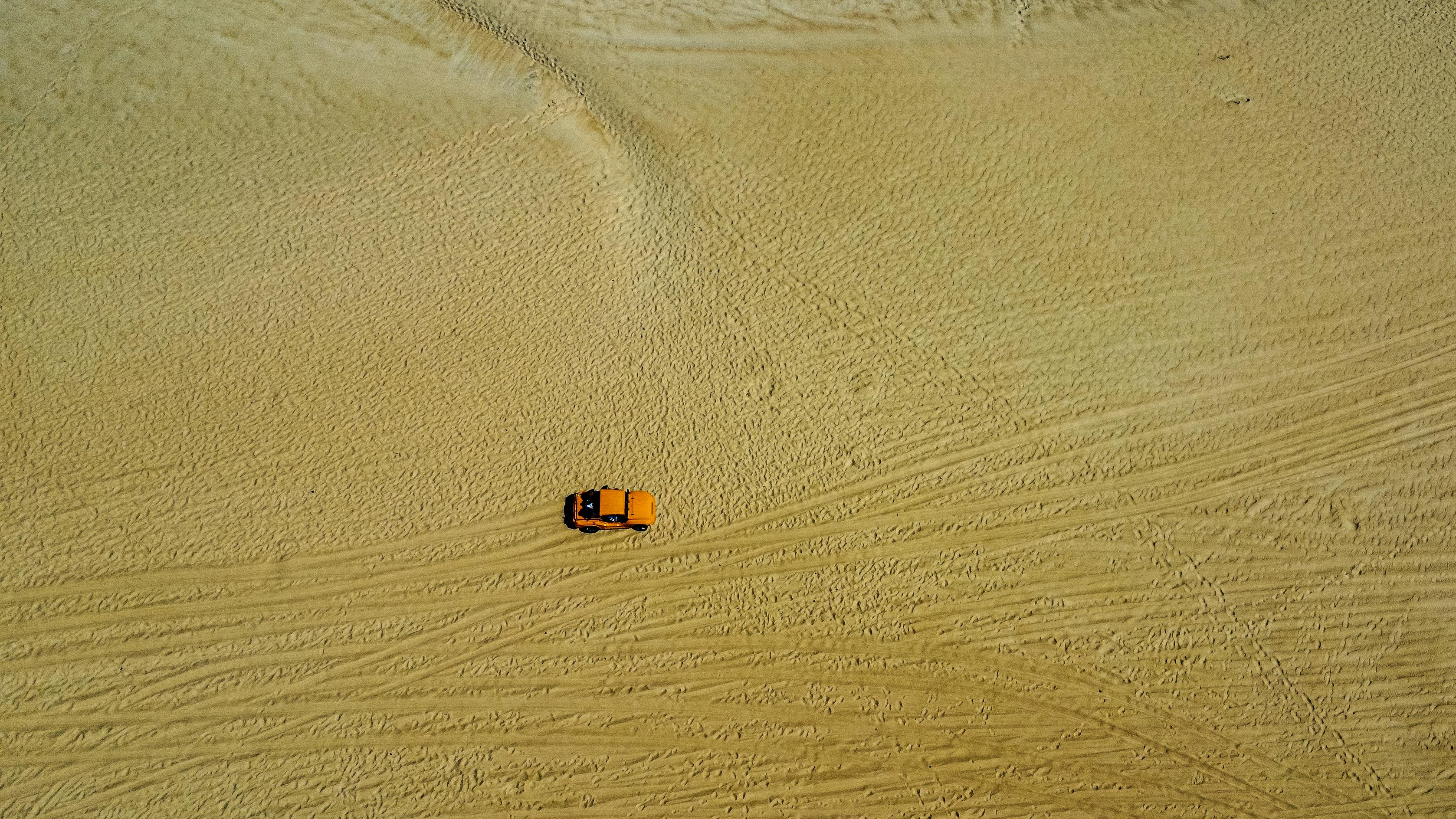 ingyenes Légifelvétel egy narancssárga járműről, amely hatalmas homokdűnéken halad Natalban, Brazíliában. Stockfotó
