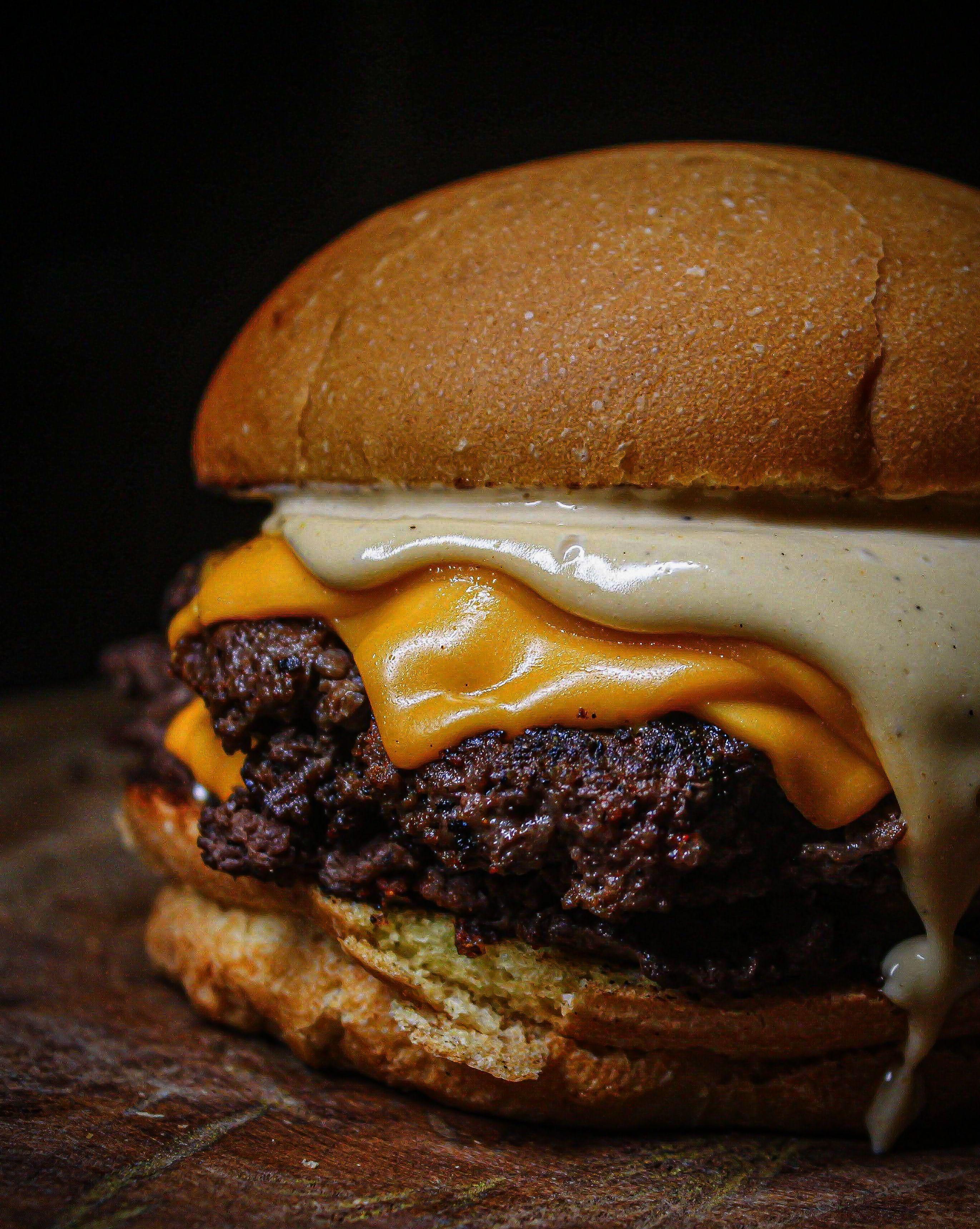 Close-up of a juicy cheeseburger with melted cheddar and a sesame seed bun.