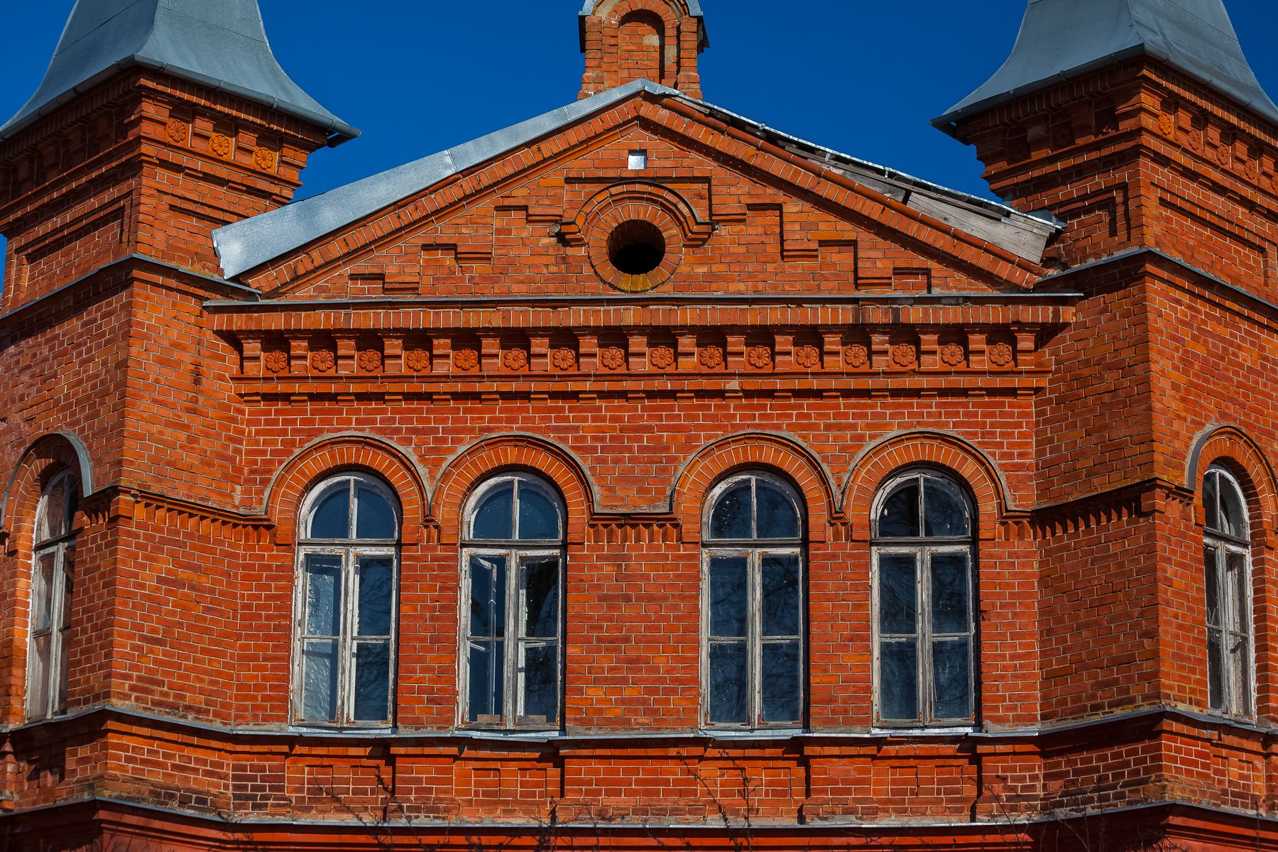 Close view of a historic red brick facade with arched windows and surviving masonry details.