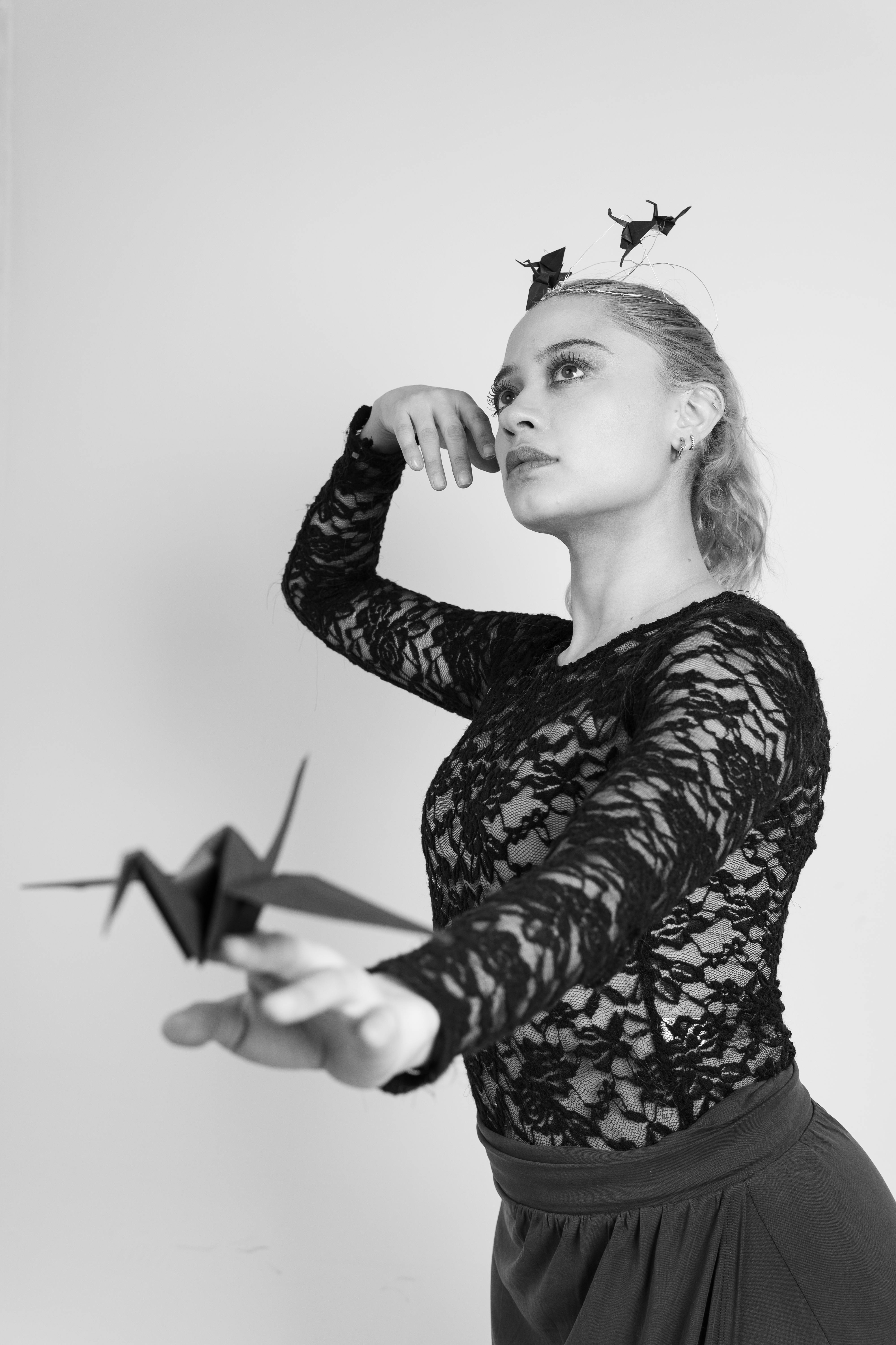 ingyenes Egy részletgazdag fekete öltözéket viselő balett-táncos kecsesen pózol egy origami daruval, megtestesítve a művészetet és az eleganciát. Stockfotó