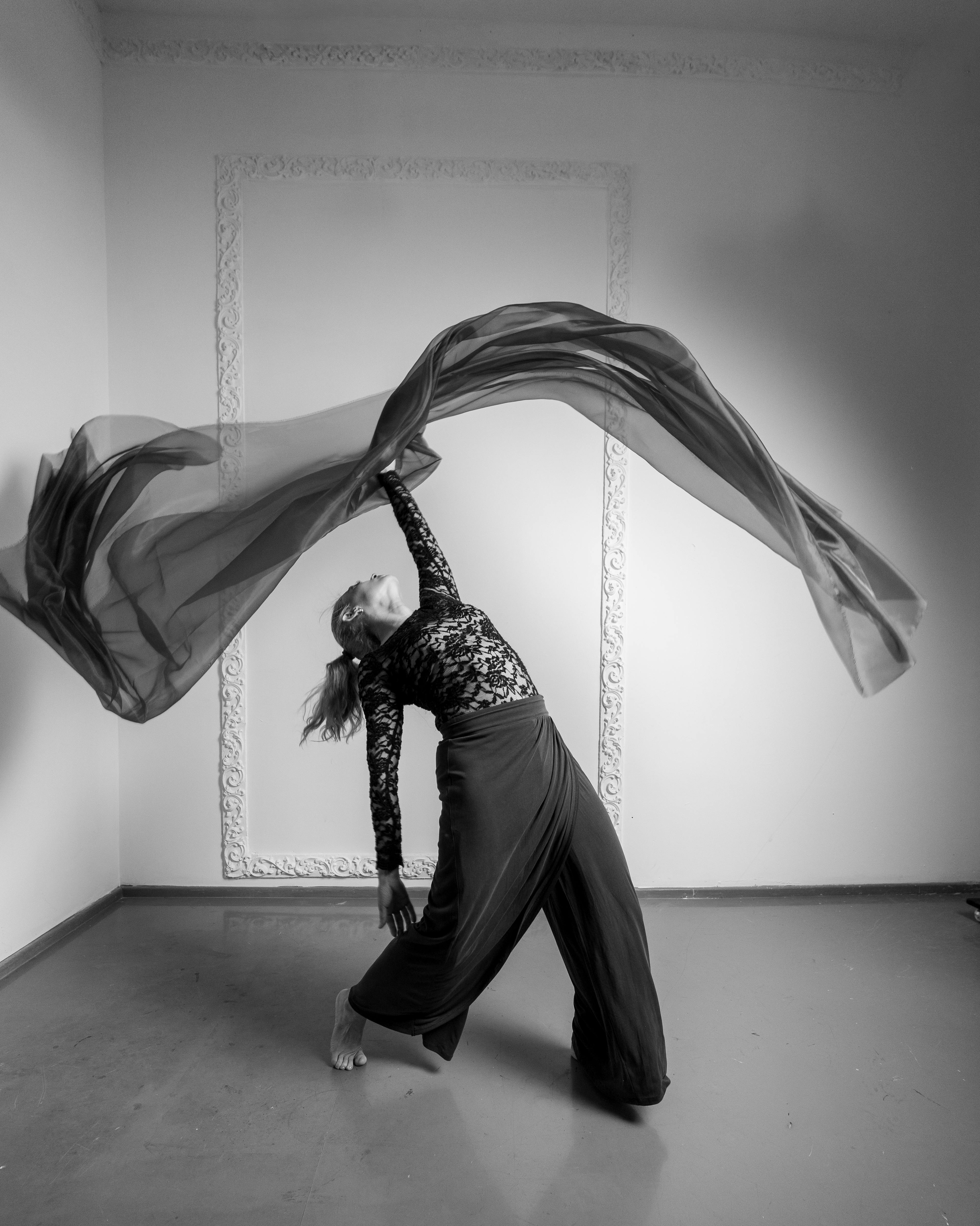 免费 一张黑白照片，展现了一位现代舞者在室内身着飘逸的布料，翩翩起舞的场景。 素材图片