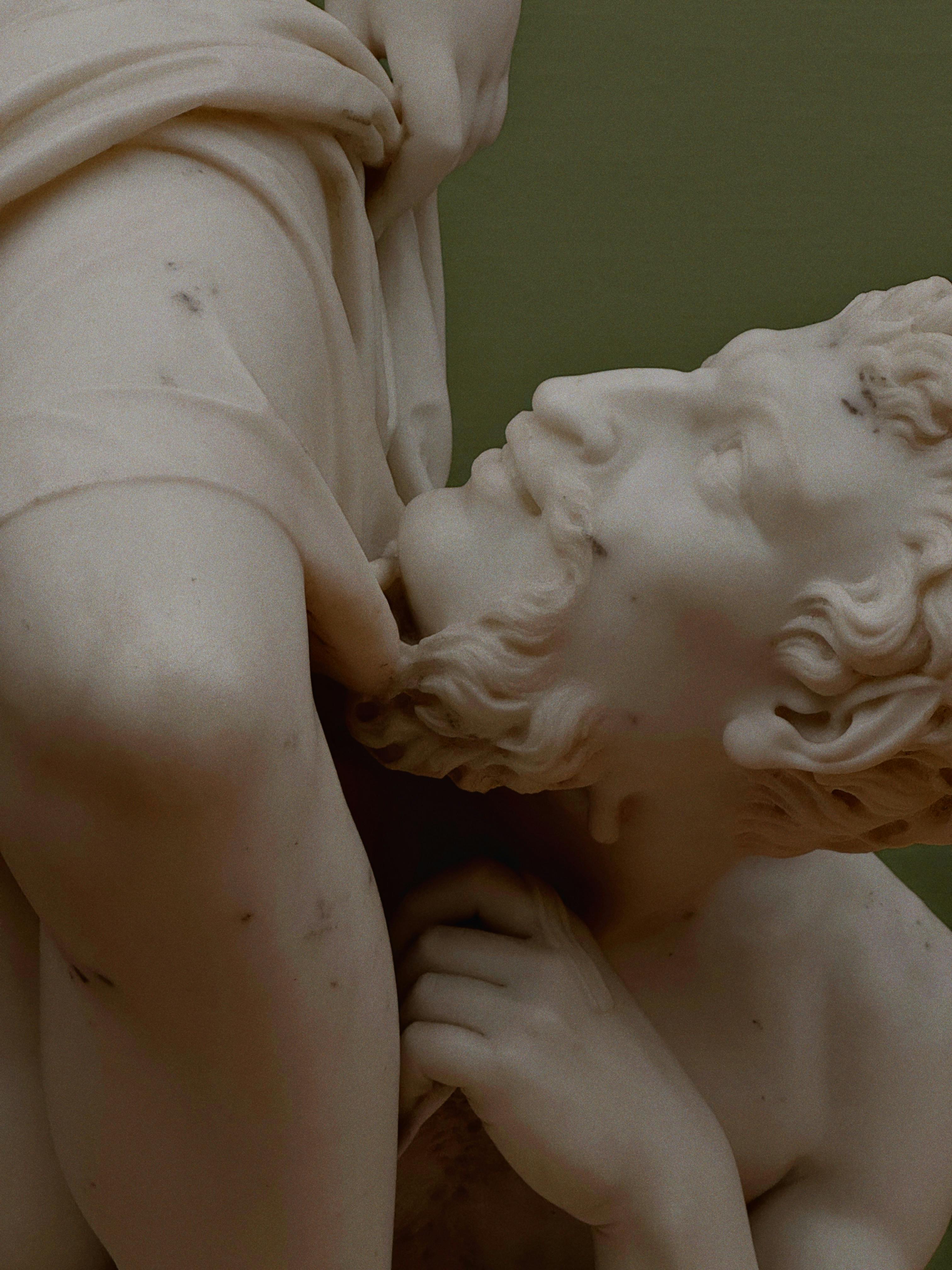 Close-up of a marble sculpture depicting an expressive mythological scene, highlighting detailed craftsmanship.