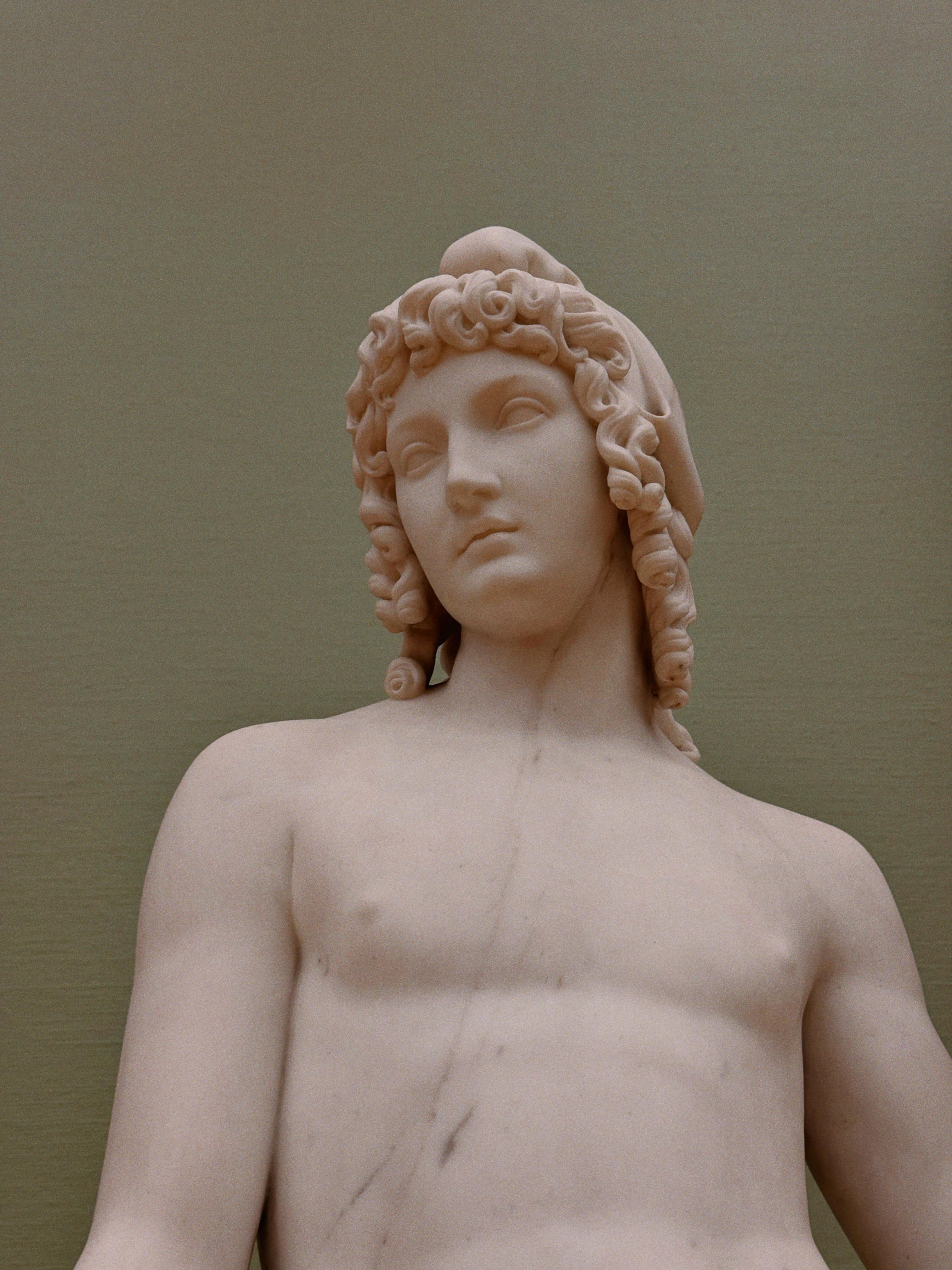 grátis Detalhe de uma estátua de mármore representando um jovem de cabelos cacheados e expressão serena. Foto profissional