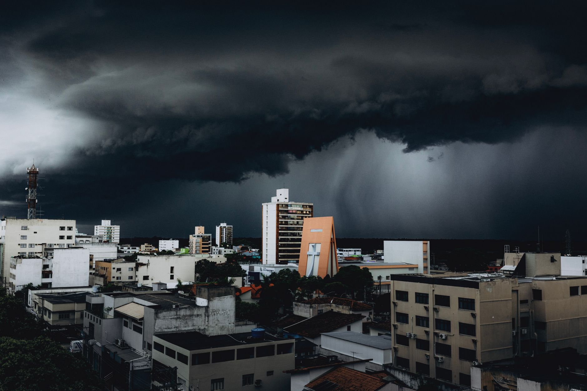 Dramatic storm clouds hover over city skyscrapers, creating a moody urban landscape contrast.