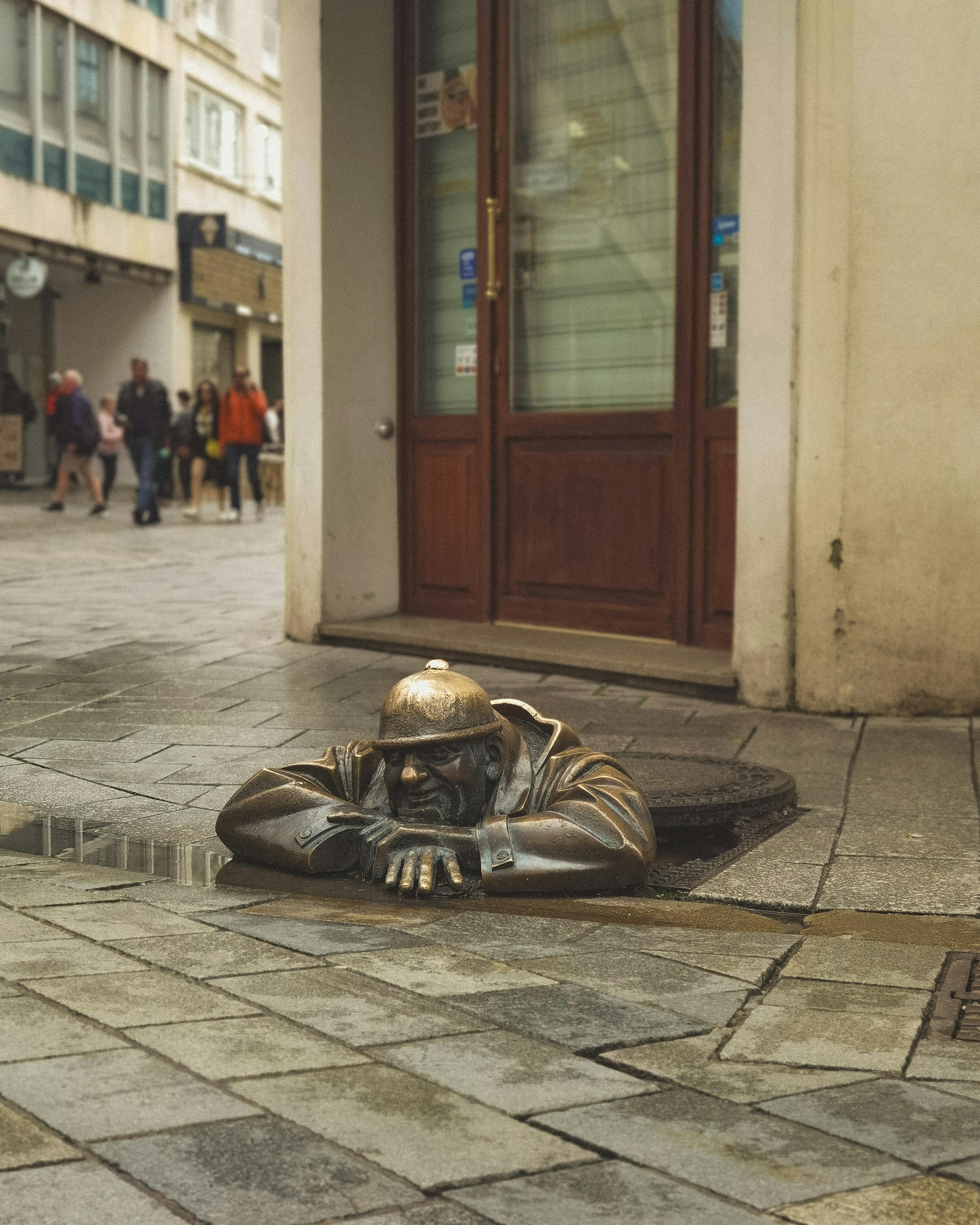 De franc Escultura única de bronze d'un home que mira des d'una claveguera al nucli antic de Bratislava. Foto d'estoc