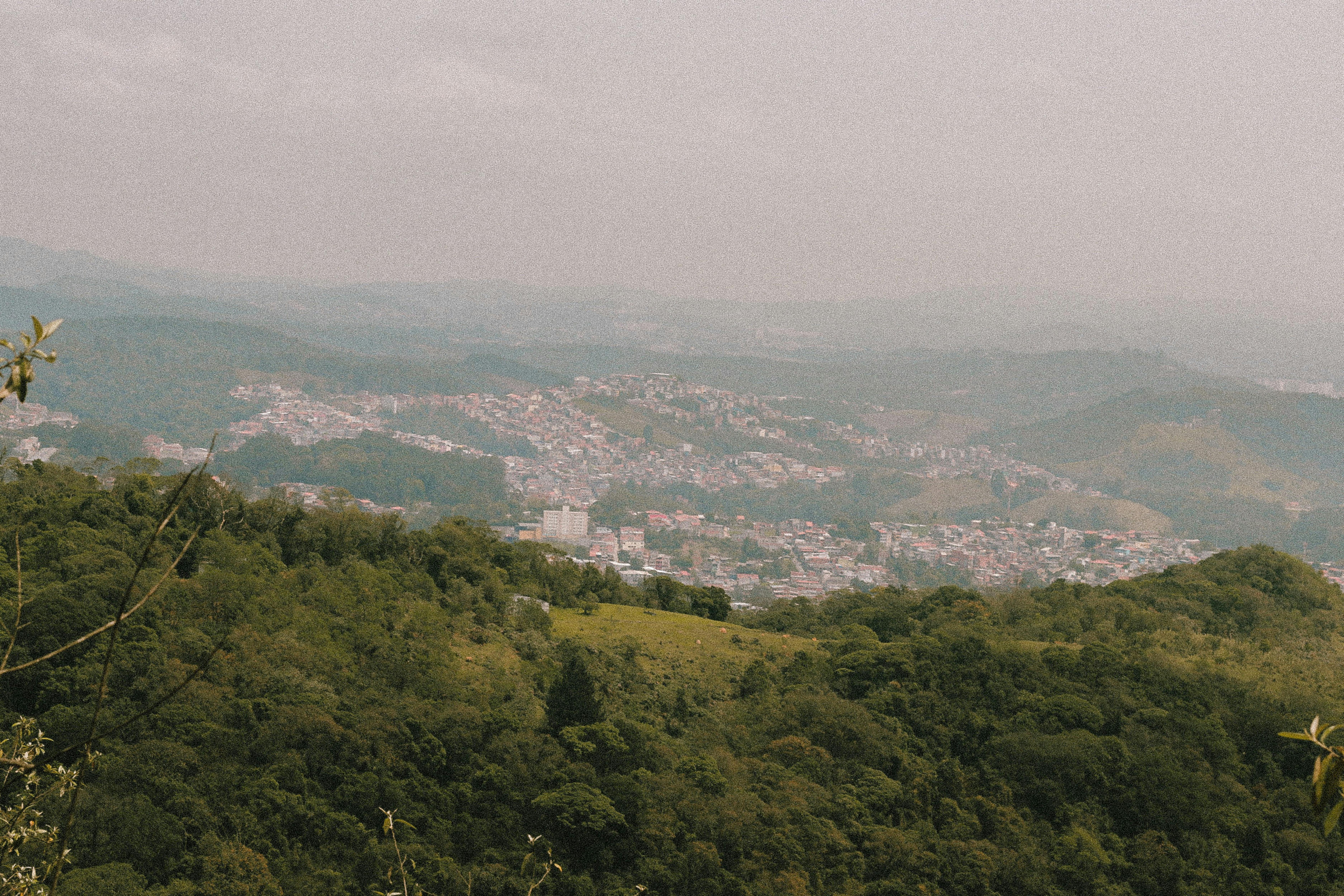 Kostenlos Ein atemberaubender Luftblick auf die grünen Hügel und die sich ausbreitende Stadtlandschaft von São Paulo unter einem nebligen Himmel. Stock-Foto