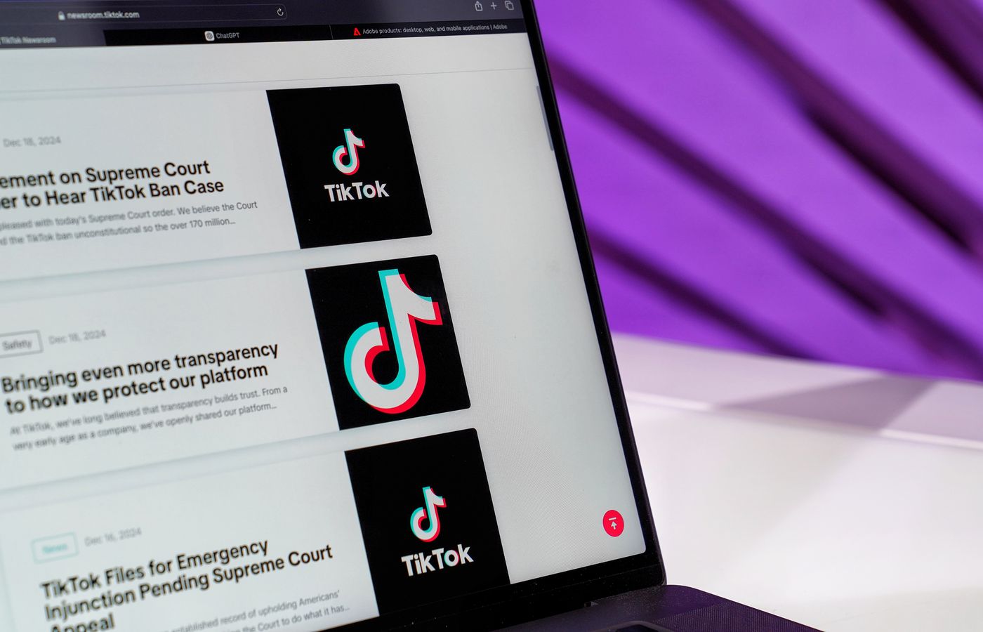 Close-up of laptop screen showing TikTok news articles with a purple background.