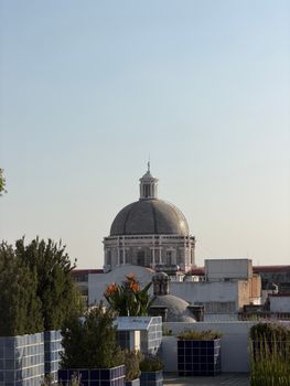 View of Puebla Cathedral dome in Mexico surrounded by urban greenery under a clear sky.