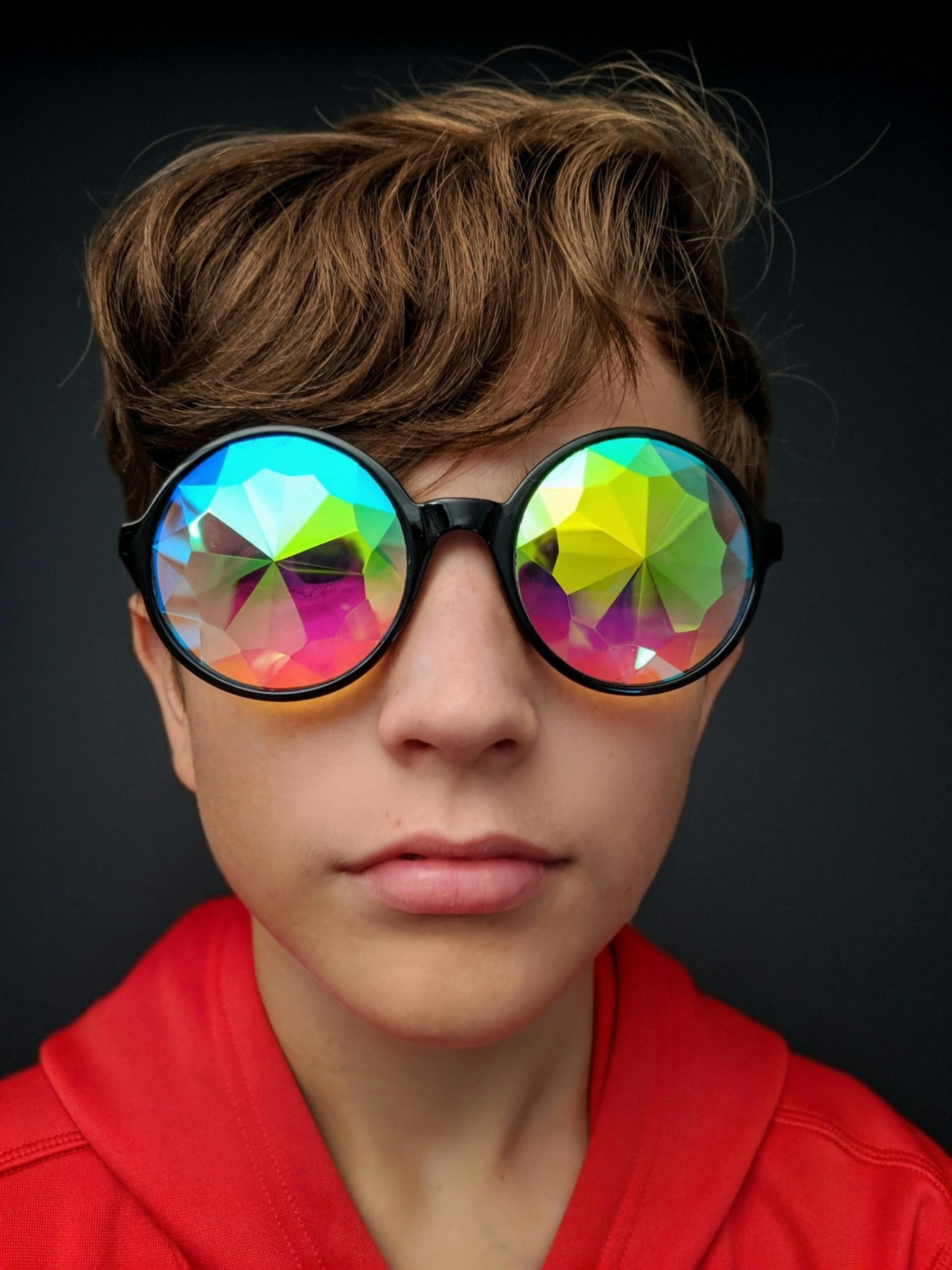 Gratuit Prim-plan al unui adolescent purtând ochelari caleidoscop cu reflexii vibrante. Portret unic și colorat. Fotografie de stoc