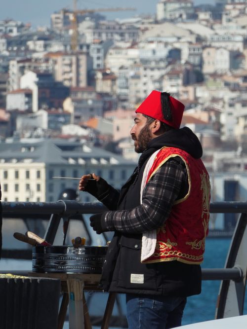 Free Street vendor wearing traditional attire cooks on Istanbul's bustling streets. Stock Photo