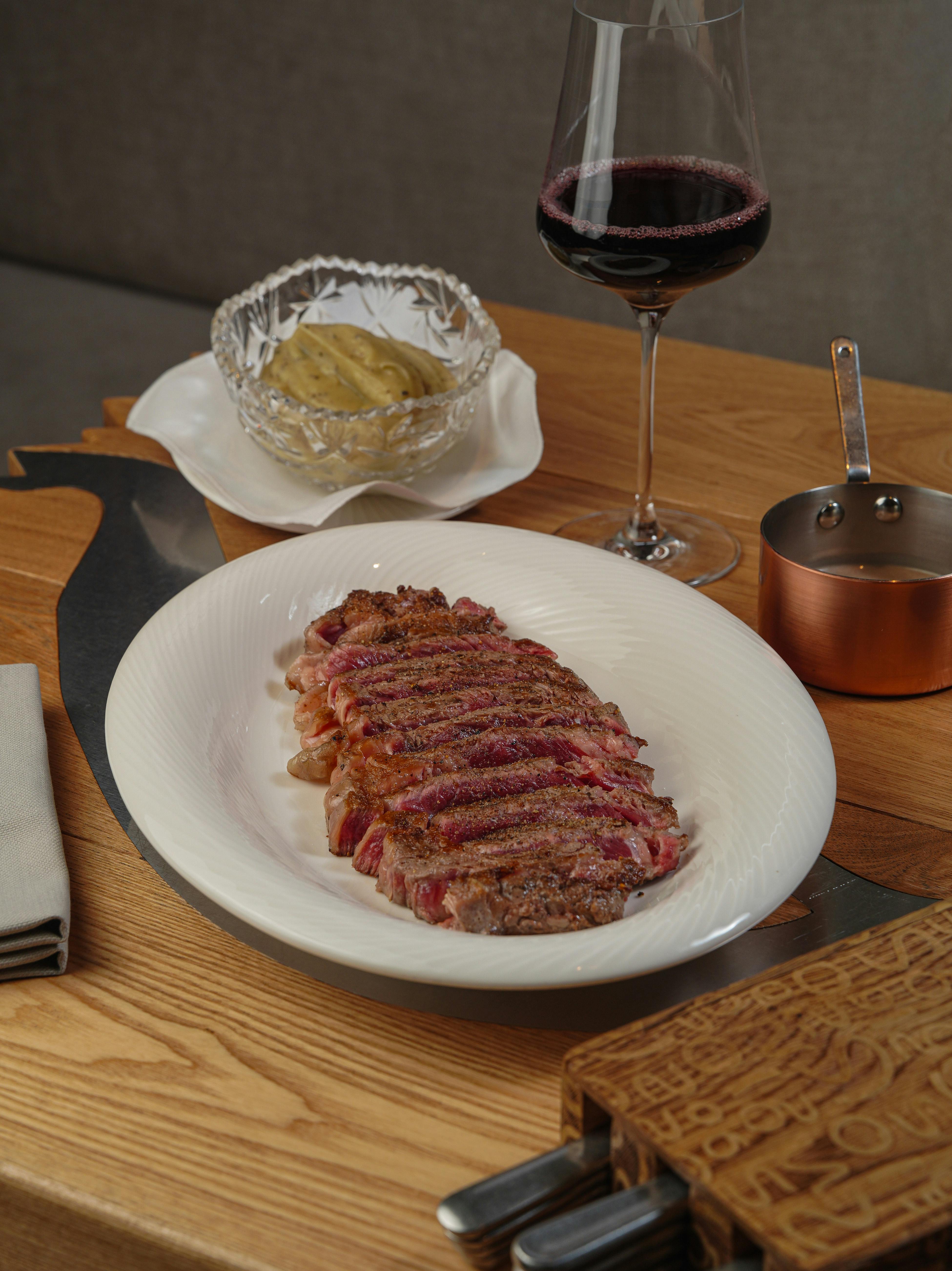 Gratis Fettine di bistecca con vino rosso, purè di patate e salsa su un tavolo di legno. Foto a disposizione