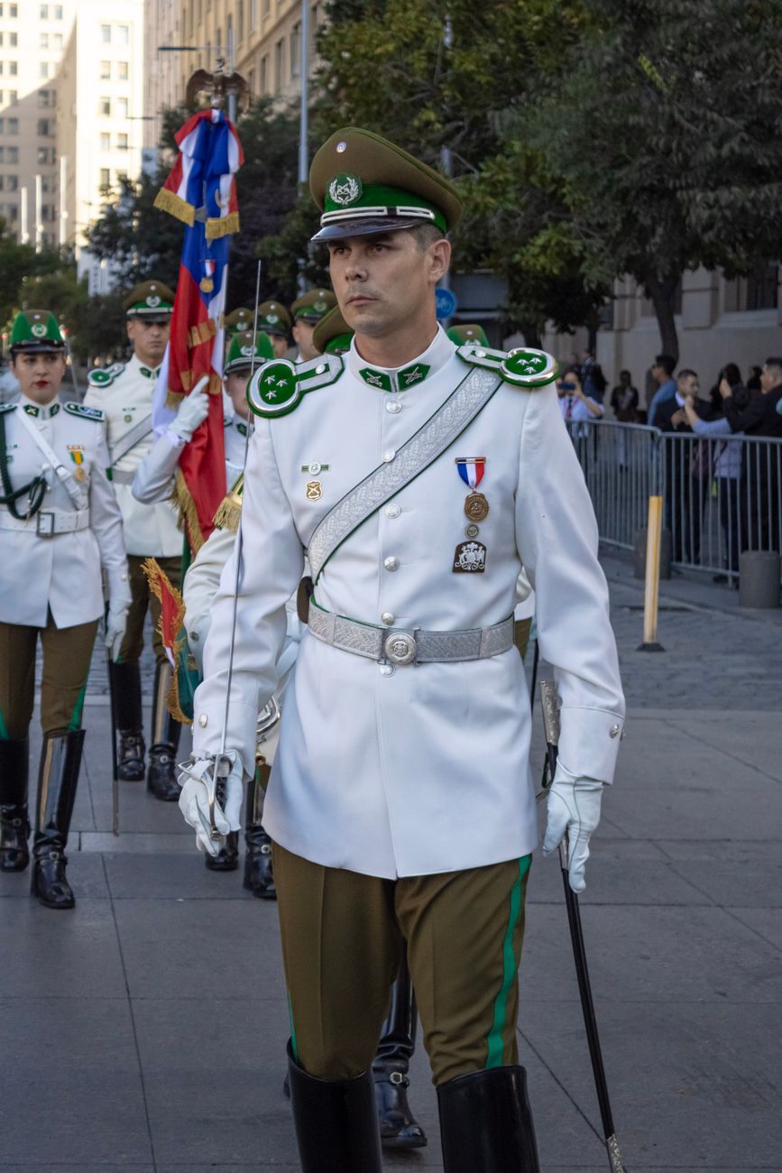 Uma procissão formal de oficiais da Carabinieri chilena em Santiago em um dia ensolarado.