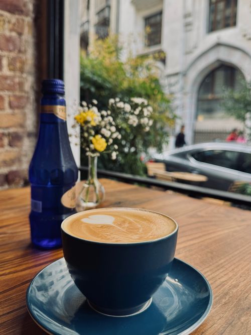 Free Warm cafe ambiance with a latte and fresh flowers by the window. Stock Photo