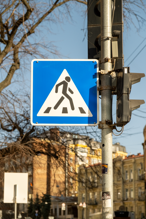 Free A pedestrian crossing sign on a sunny day in a cityscape. Stock Photo