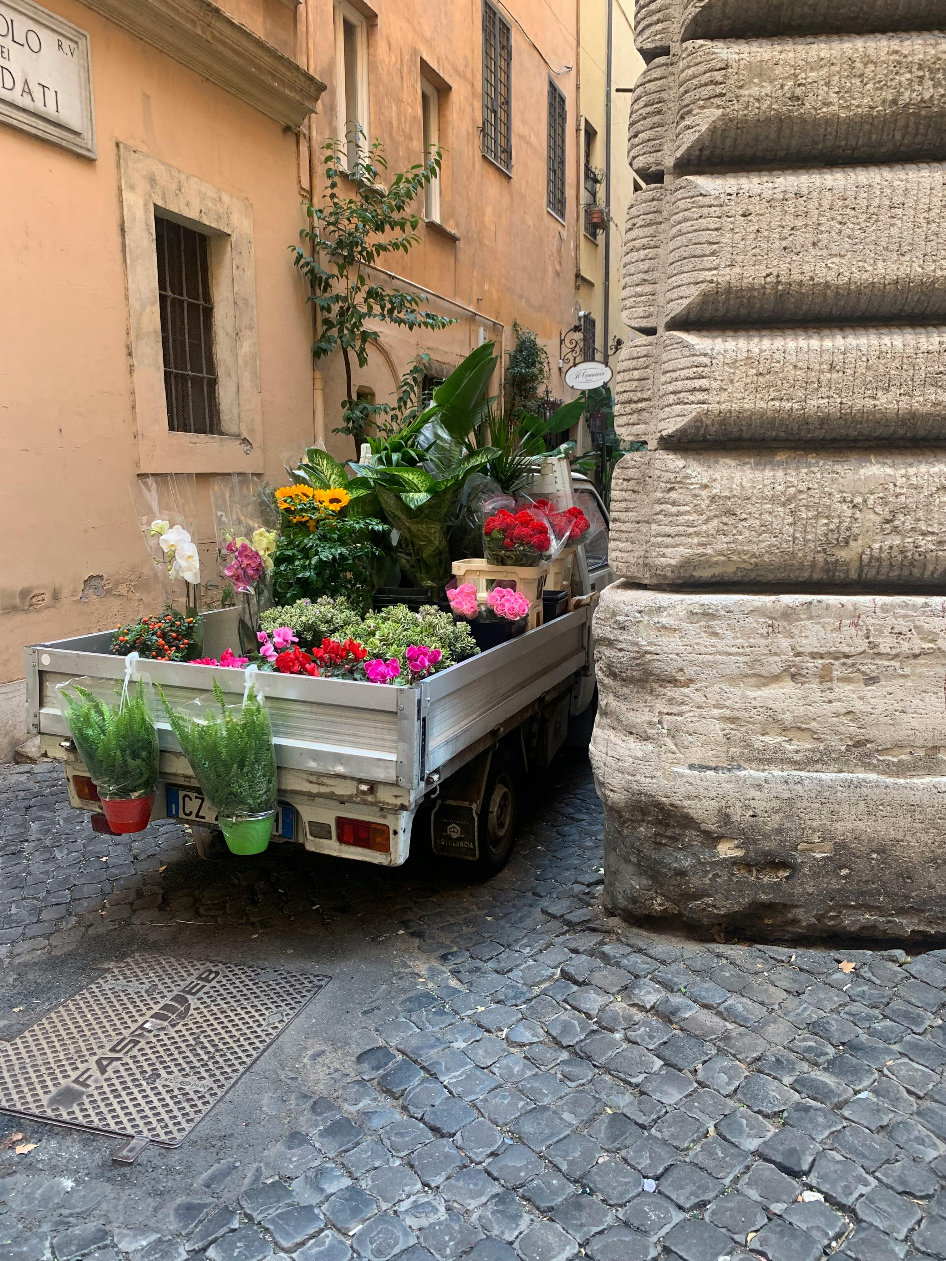 Δωρεάν Ένα γραφικό καρότσι δρόμου γεμάτο με πολύχρωμα λουλούδια παρκαρισμένο σε ένα στενό σοκάκι της πόλης. Φωτογραφία από στοκ φωτογραφιών