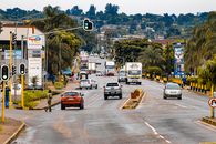 A bustling street view in Bhunya, Eswatini with traffic and pedestrians amidst lush greenery.