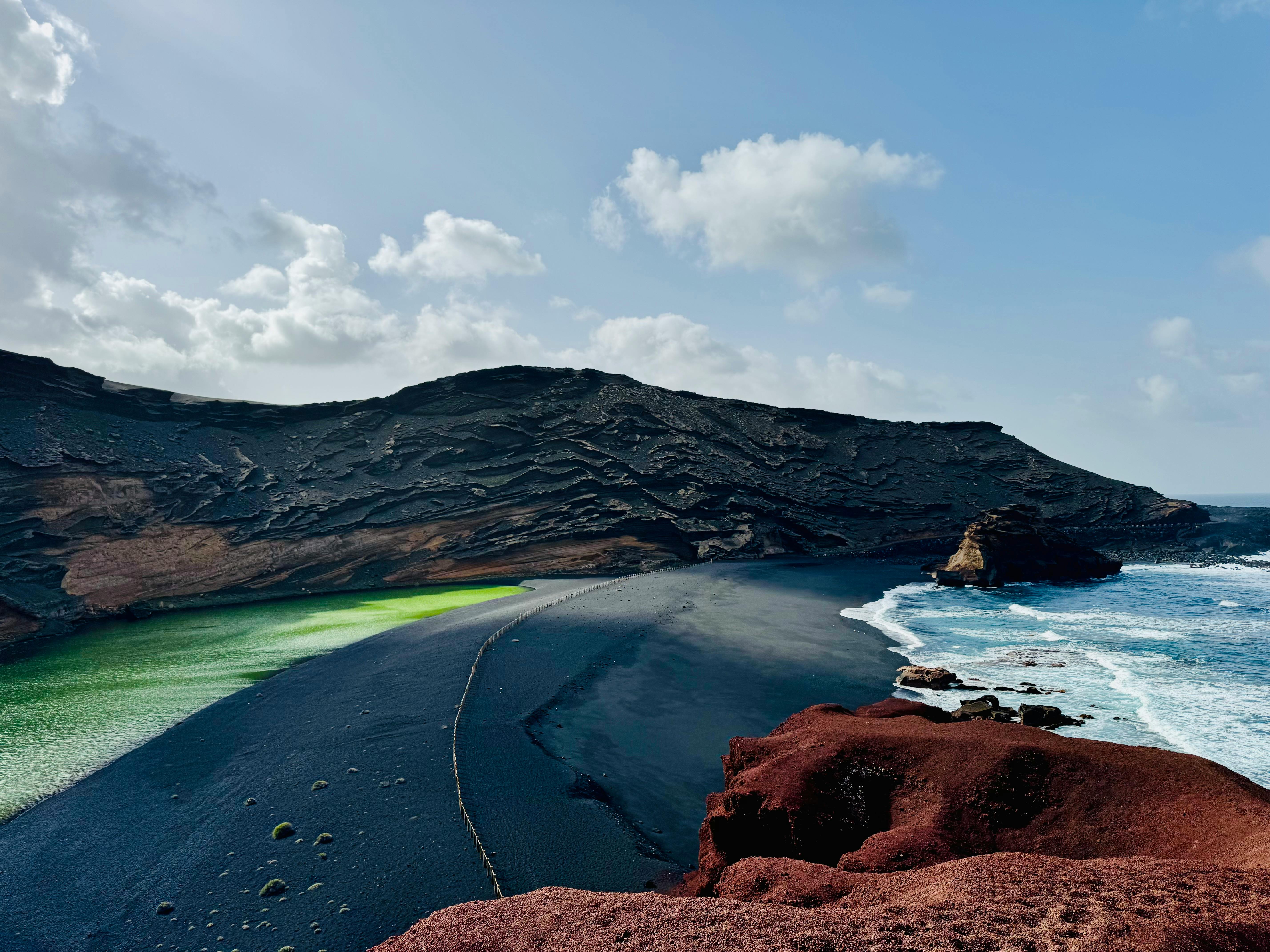 Explore the dramatic volcanic landscape of El Golfo, Lanzarote, with its vibrant green lagoon and striking black sand beach.