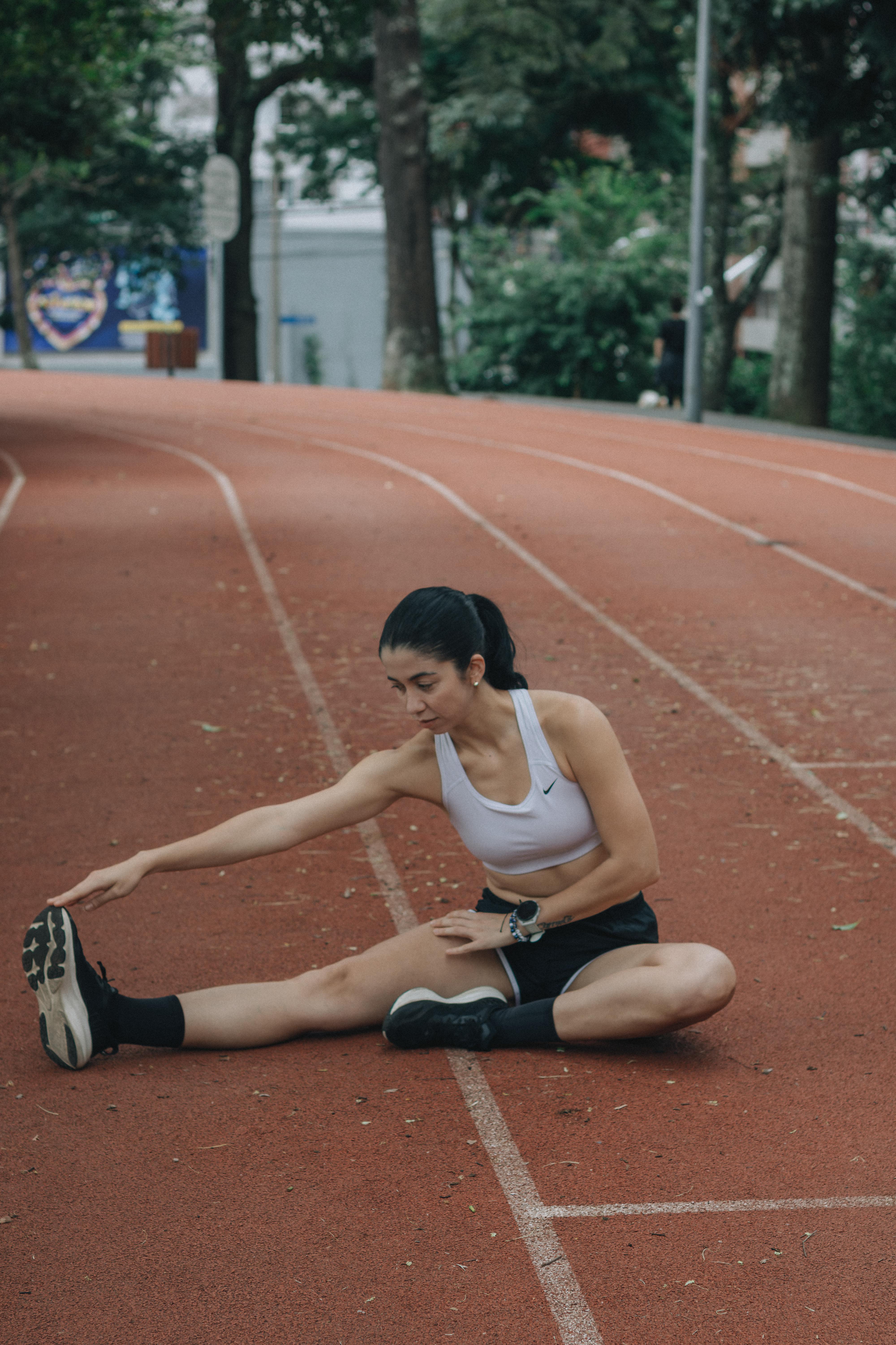 ฟรี หญิงสาวนักกีฬา กำลังยืดกล้ามเนื้อบนลู่วิ่ง เตรียมพร้อมสำหรับการออกกำลังกาย คลังภาพถ่าย