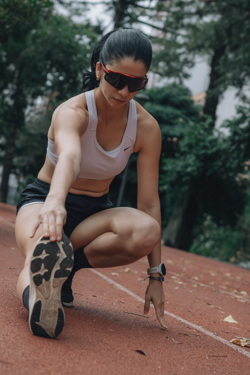 Free Athletic woman stretches before workout on outdoor track. Stock Photo