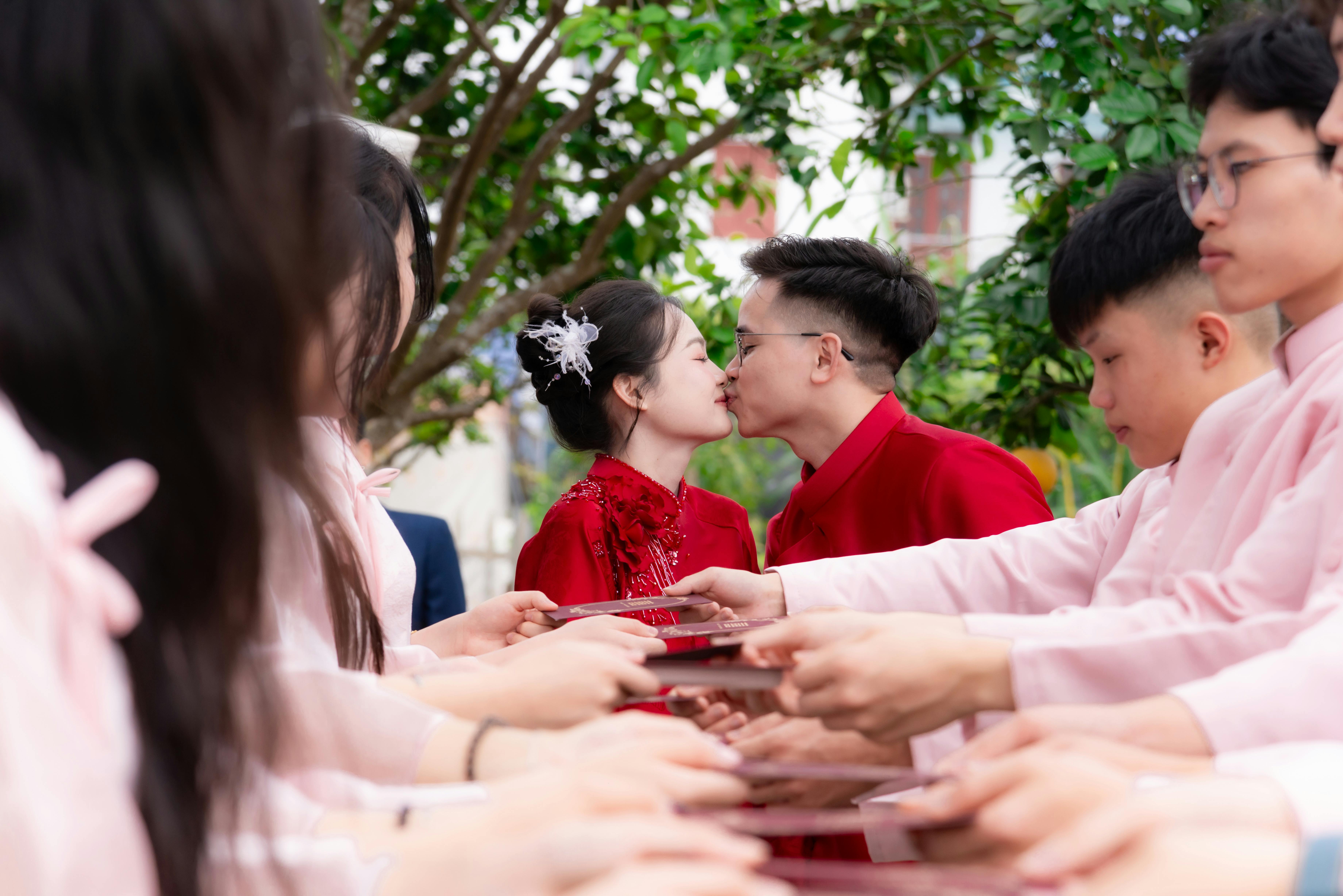 免费 在热闹的户外婚礼仪式上，一对新人与朋友们深情拥吻。 素材图片