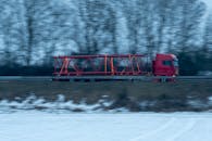 Red Truck Transporting Large Steel Beam in Motion