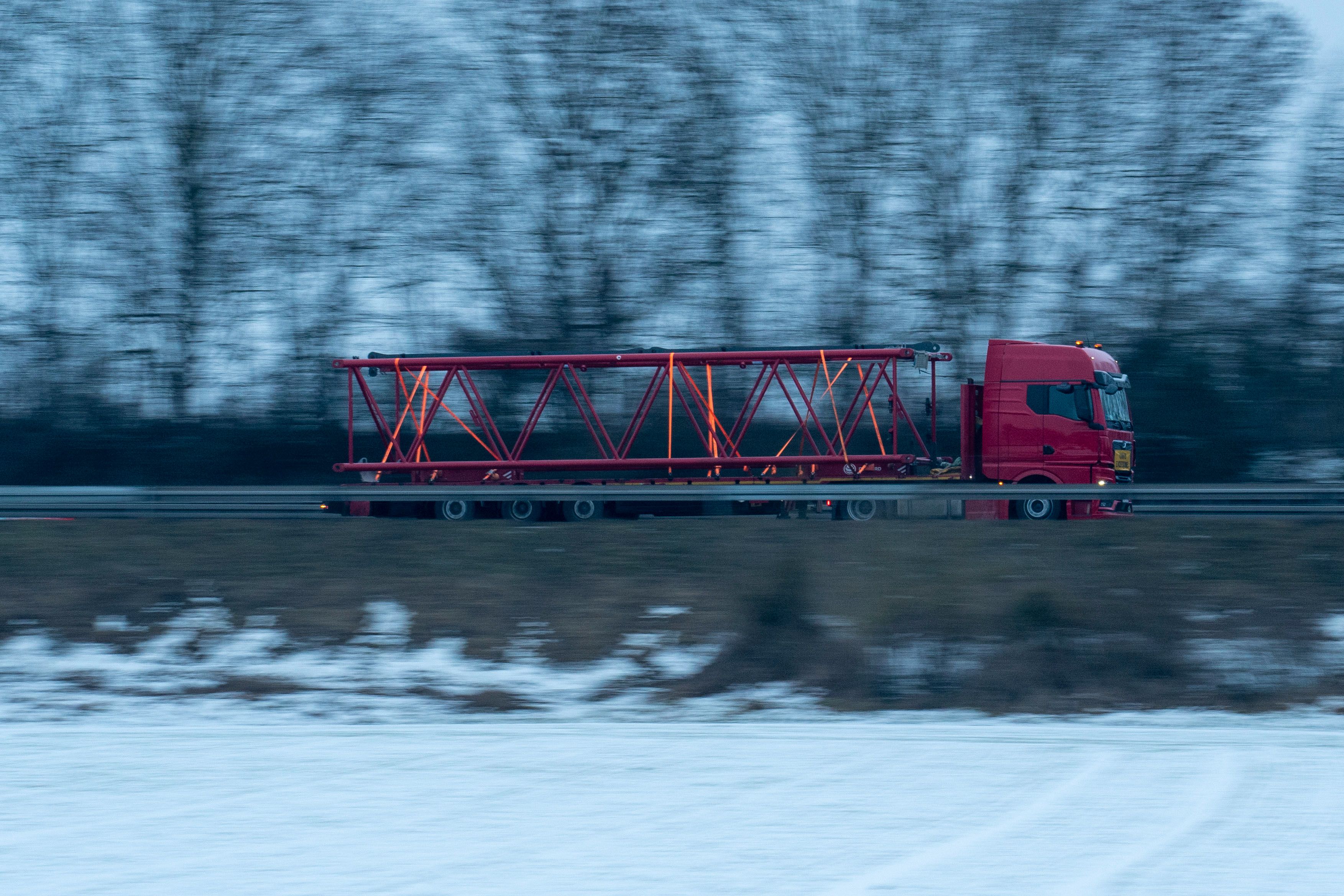 Gratis En rød lastbil med en stor stålbjælke på en snedækket motorvej om vinteren. Lagerfoto