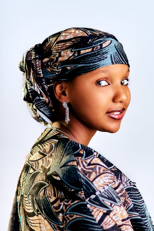 Free A woman in traditional attire with a patterned headscarf and earrings, looking over her shoulder. Stock Photo