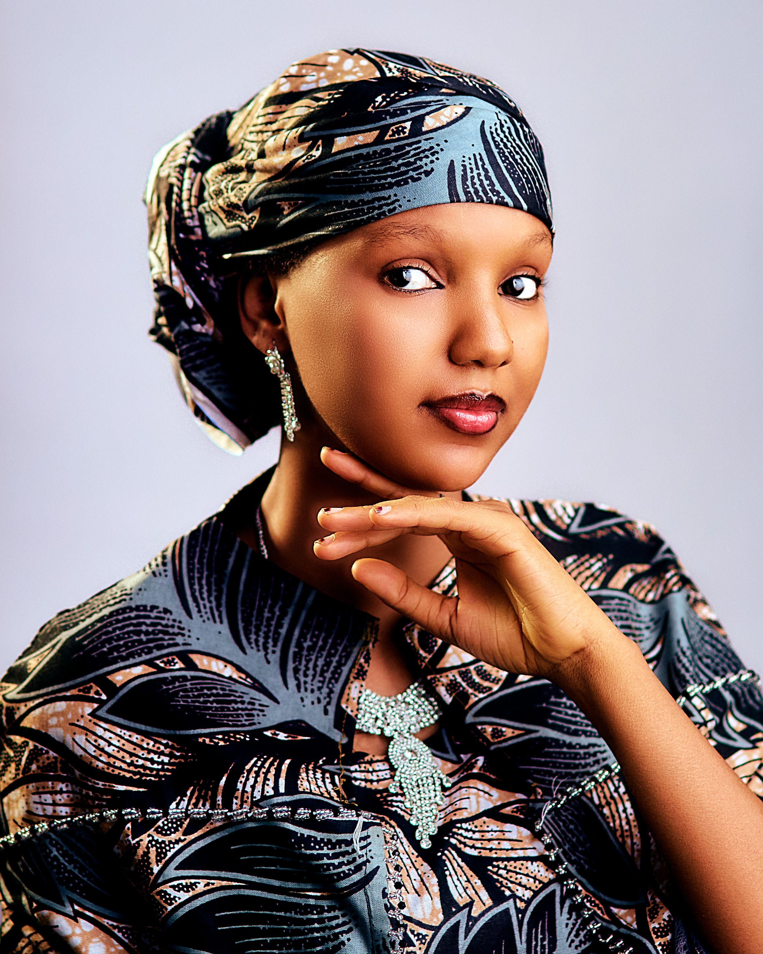 Elegant portrait of a woman in vibrant African clothing and headwrap.