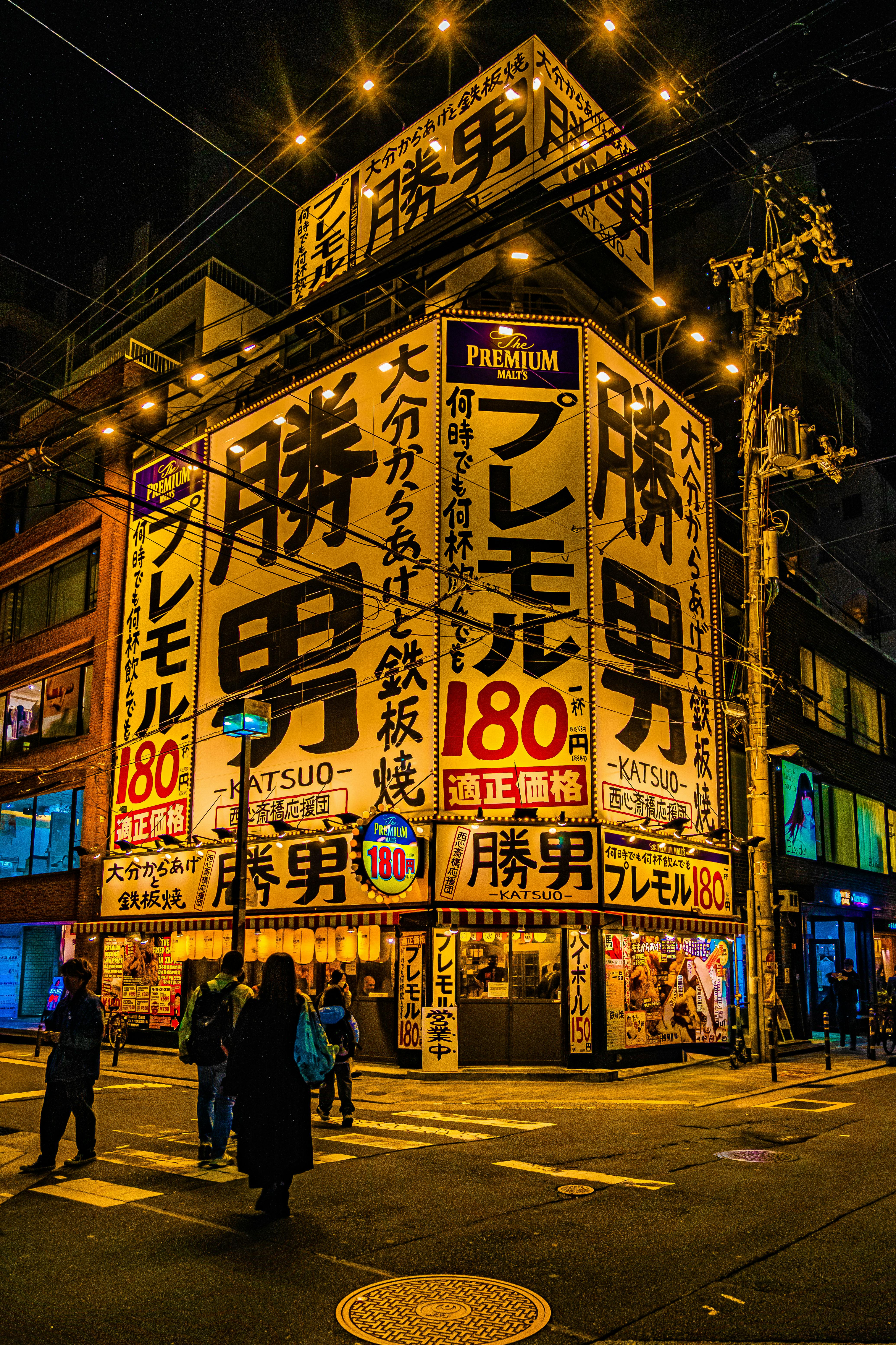 grátis Luzes de néon coloridas iluminam uma esquina movimentada no distrito de Dotonbori, em Osaka, à noite. Foto profissional