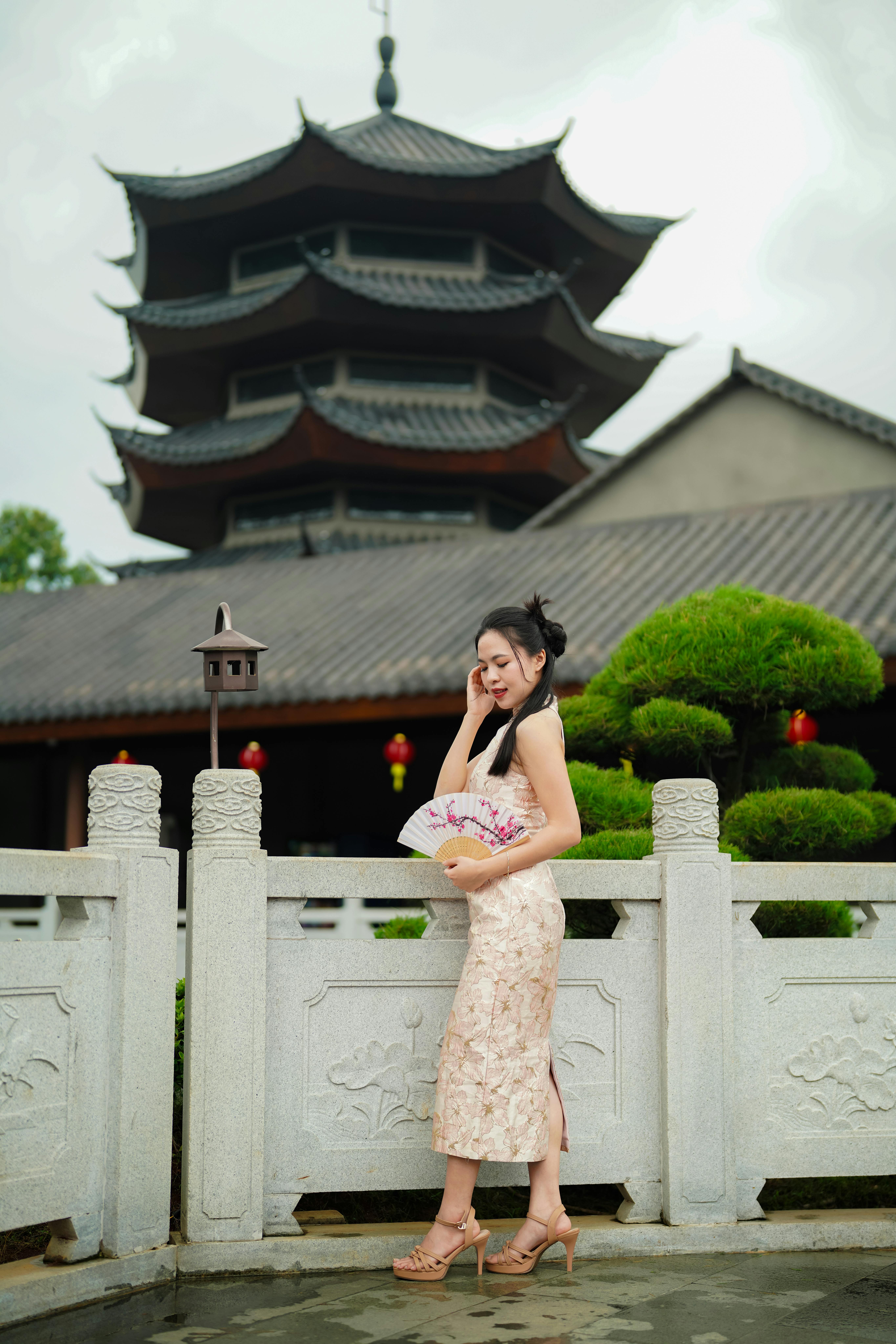 Woman standing by a pagoda in traditional attire, showcasing cultural architecture.