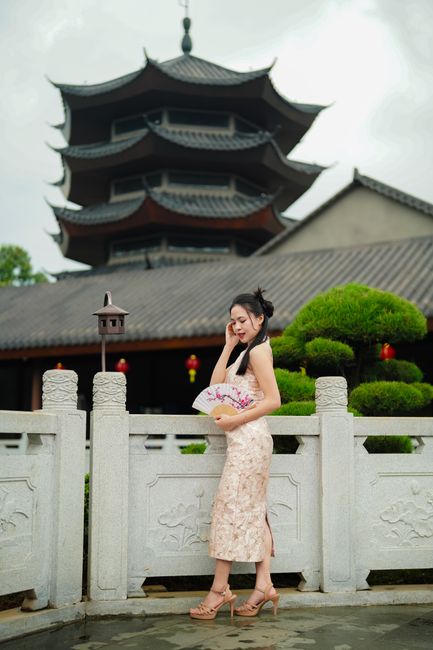 Woman standing by a pagoda in traditional attire, showcasing cultural architecture.