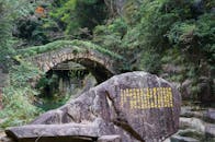 Ancient Stone Bridge and Inscribed Rock in Lush Forest