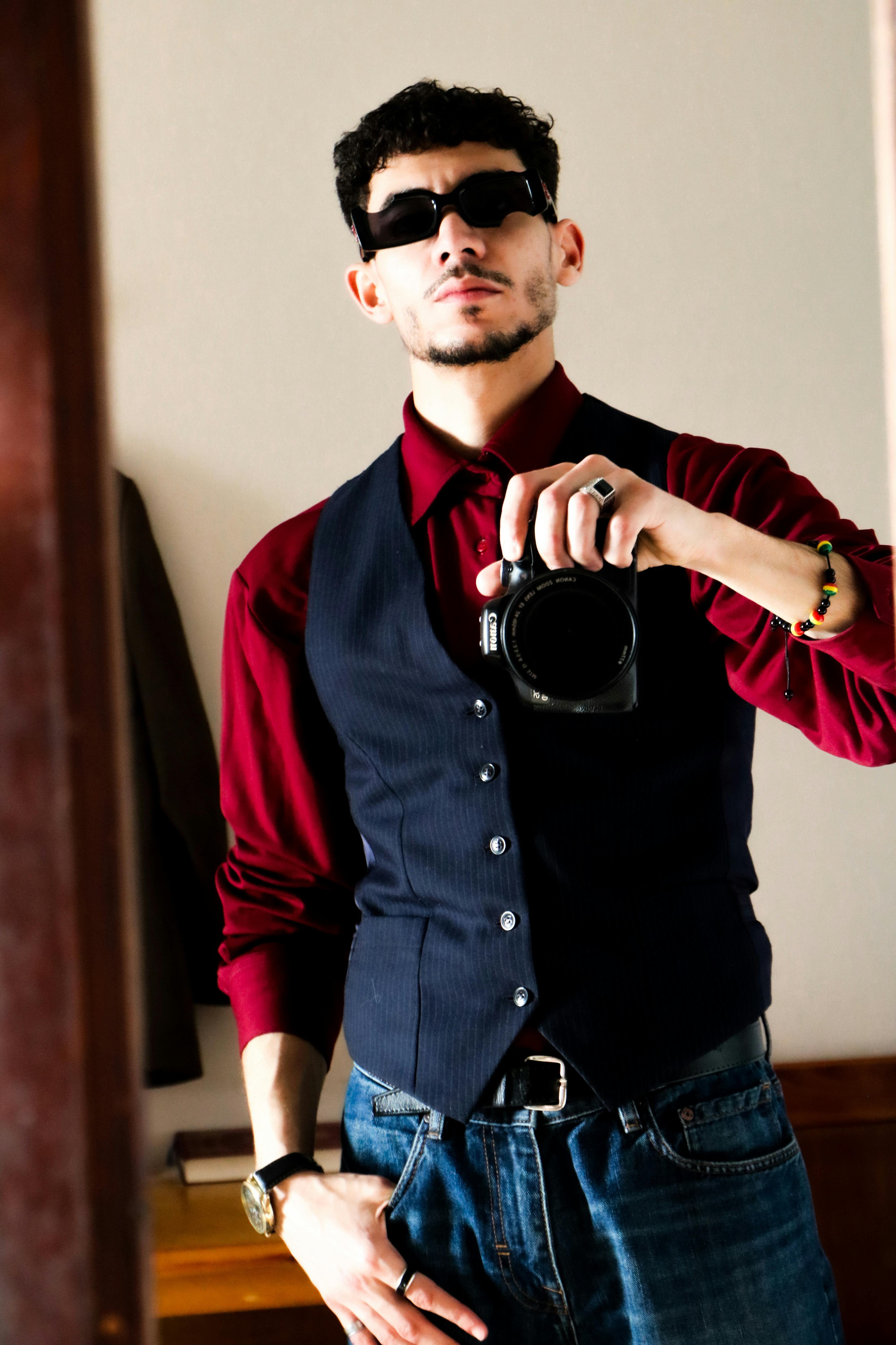 Gratuit Un bărbat încrezător, în cămașă și vestă roșii, își face un selfie cu un aparat foto DSLR în oglindă. Fotografie de stoc