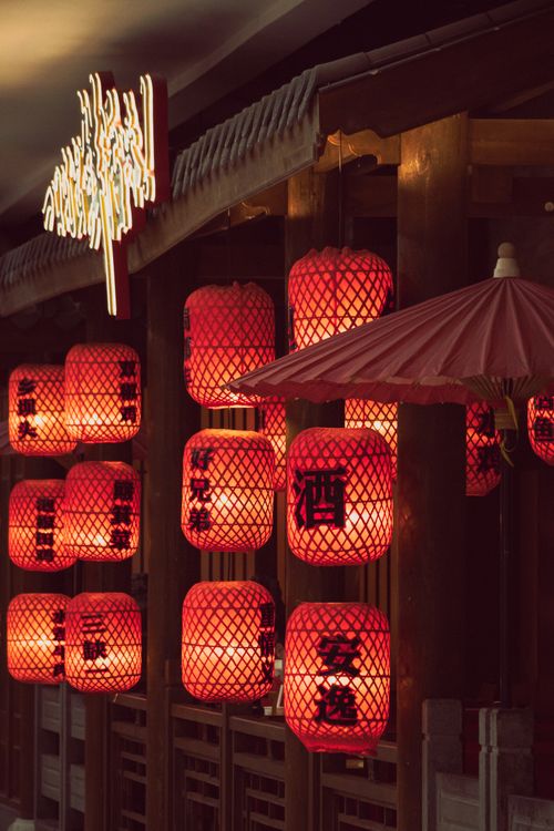 Free Traditional red Japanese lanterns hanging in a dimly lit market street, creating a warm ambiance. Stock Photo