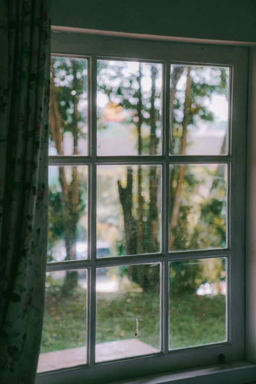 Free A rustic window with a view of trees and greenery creating a peaceful indoor-outdoor connection. Stock Photo