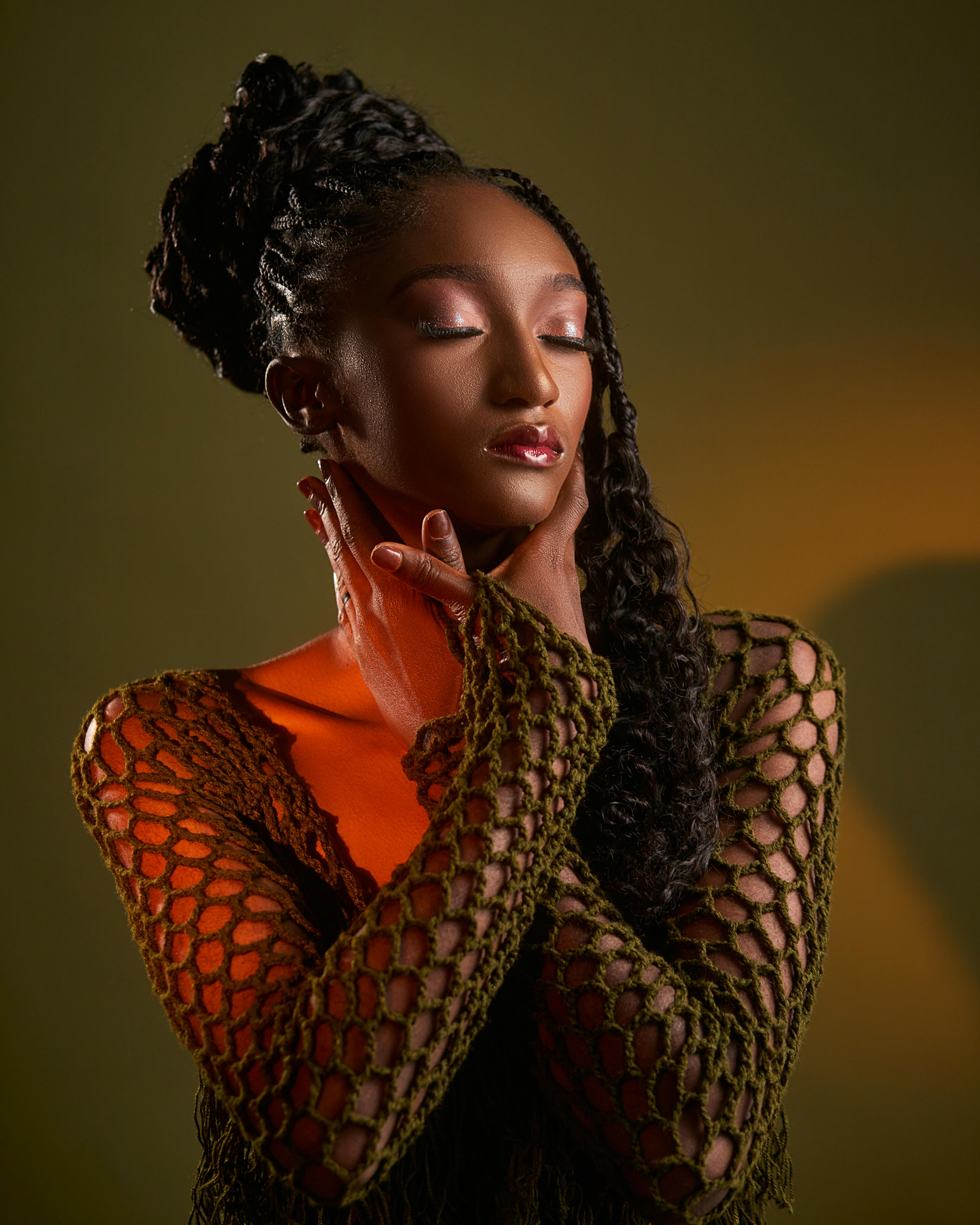 bezplatná Portrét ženy s copánkovým účesem ve stylovém síťovaném oblečení na hnědém pozadí. Základová fotografie