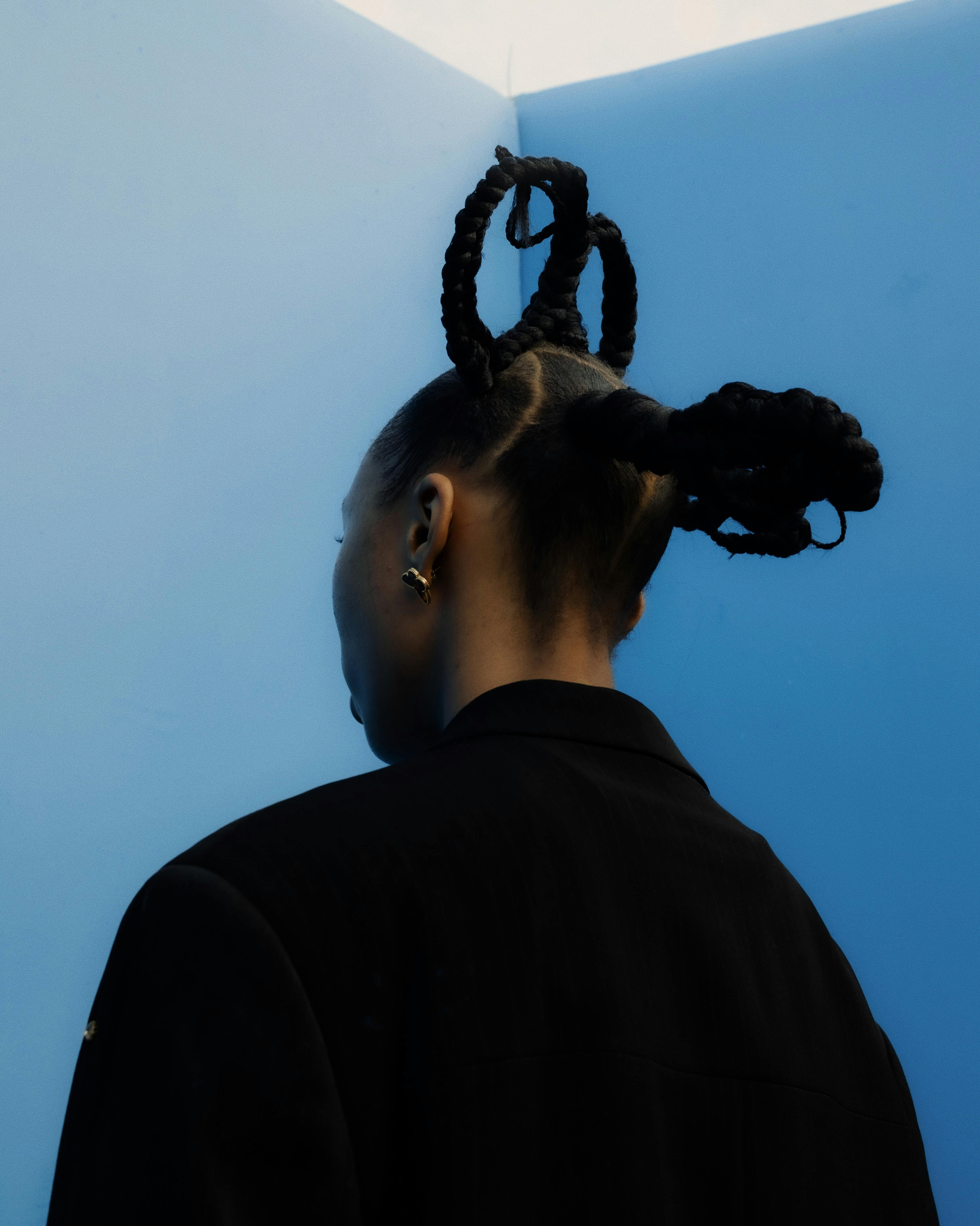 Безкоштовне Захопливий художній портрет жінки з вишуканою плетеною зачіскою на яскраво-блакитному тлі. стокове фото