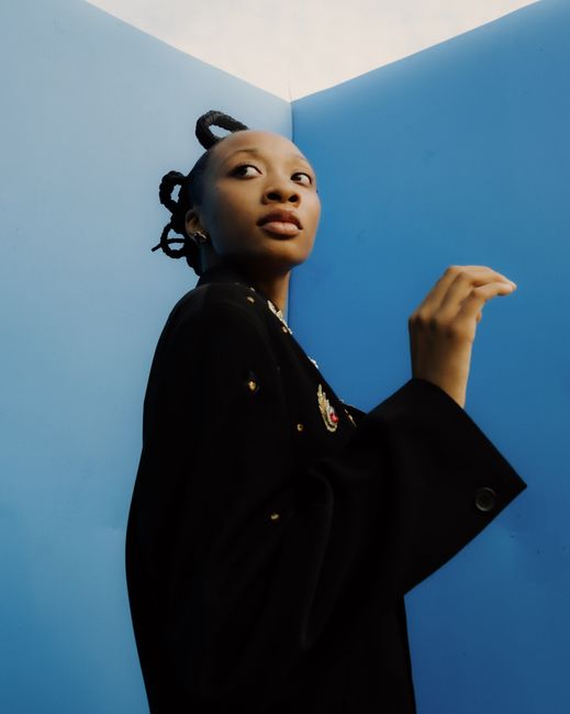 Stylish editorial portrait of a woman with unique hairstyle against a blue backdrop.