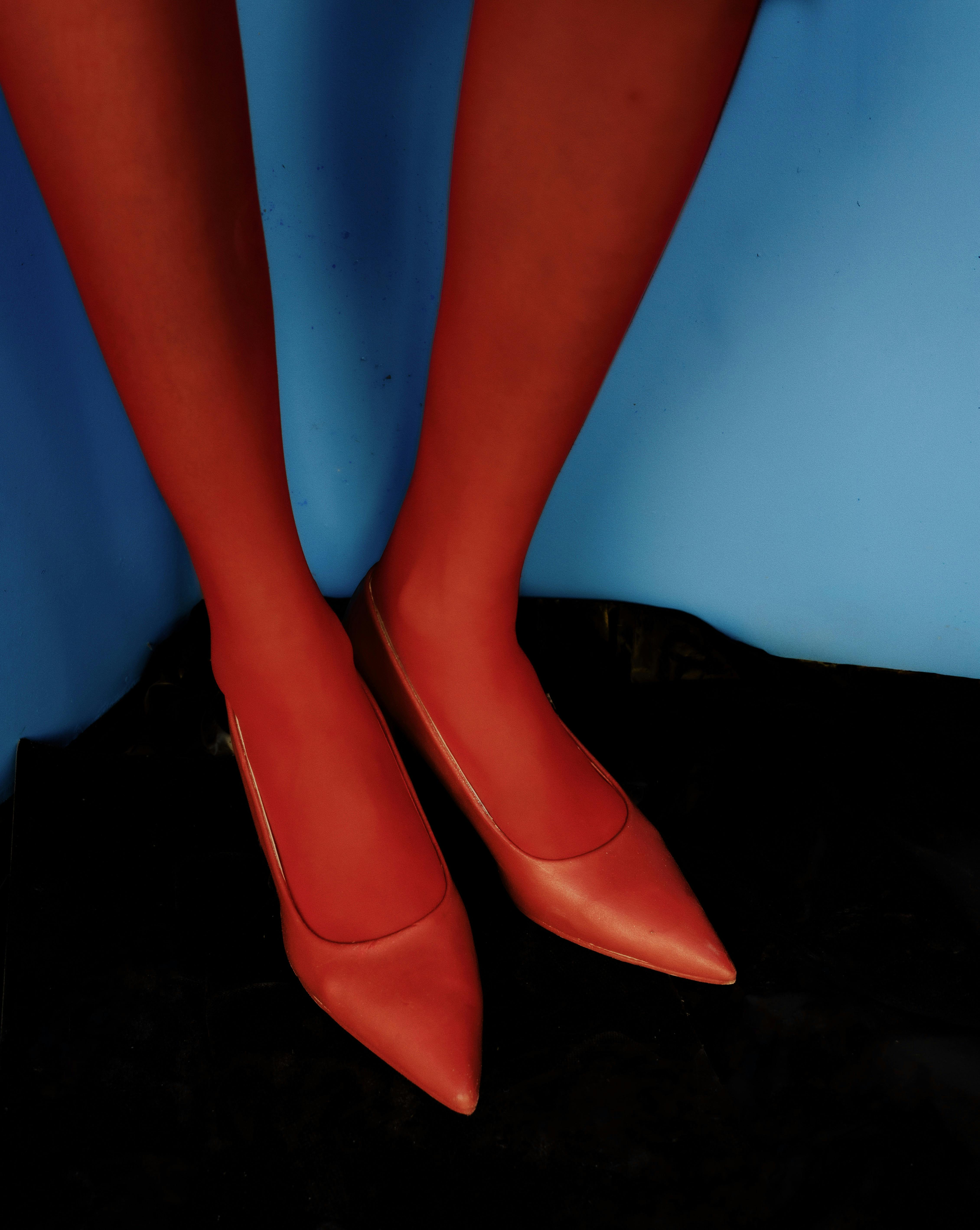 Безкоштовне Червоні туфлі на гострому підборі з ефектним контрастом на яскраво-синьому фоні. Модний знімок. стокове фото