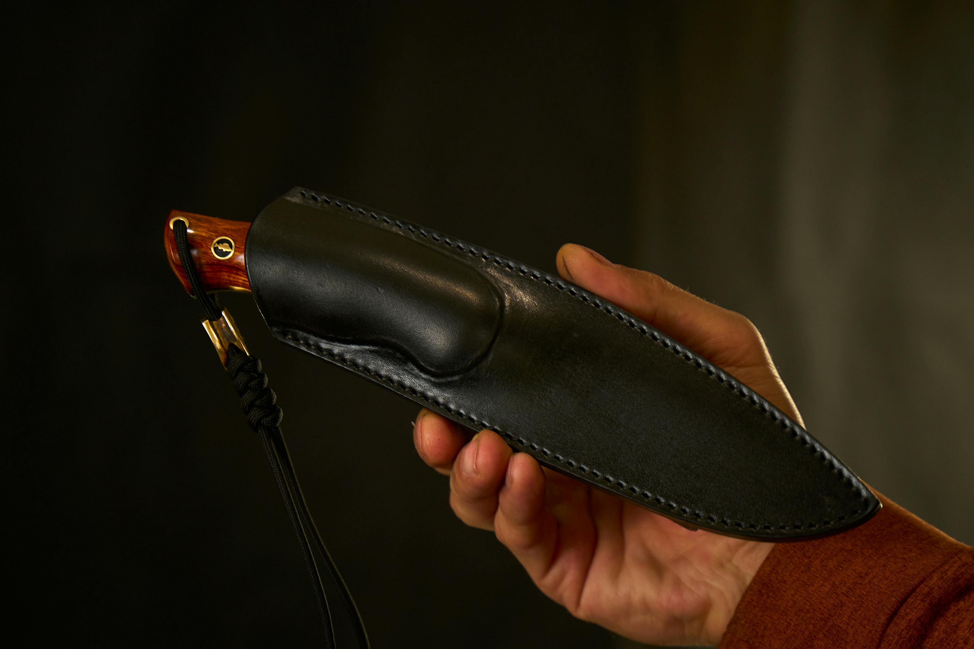 Kostnadsfria Närbild av en handgjord kniv med läderslida som hålls av en vuxen hand. Stock foto