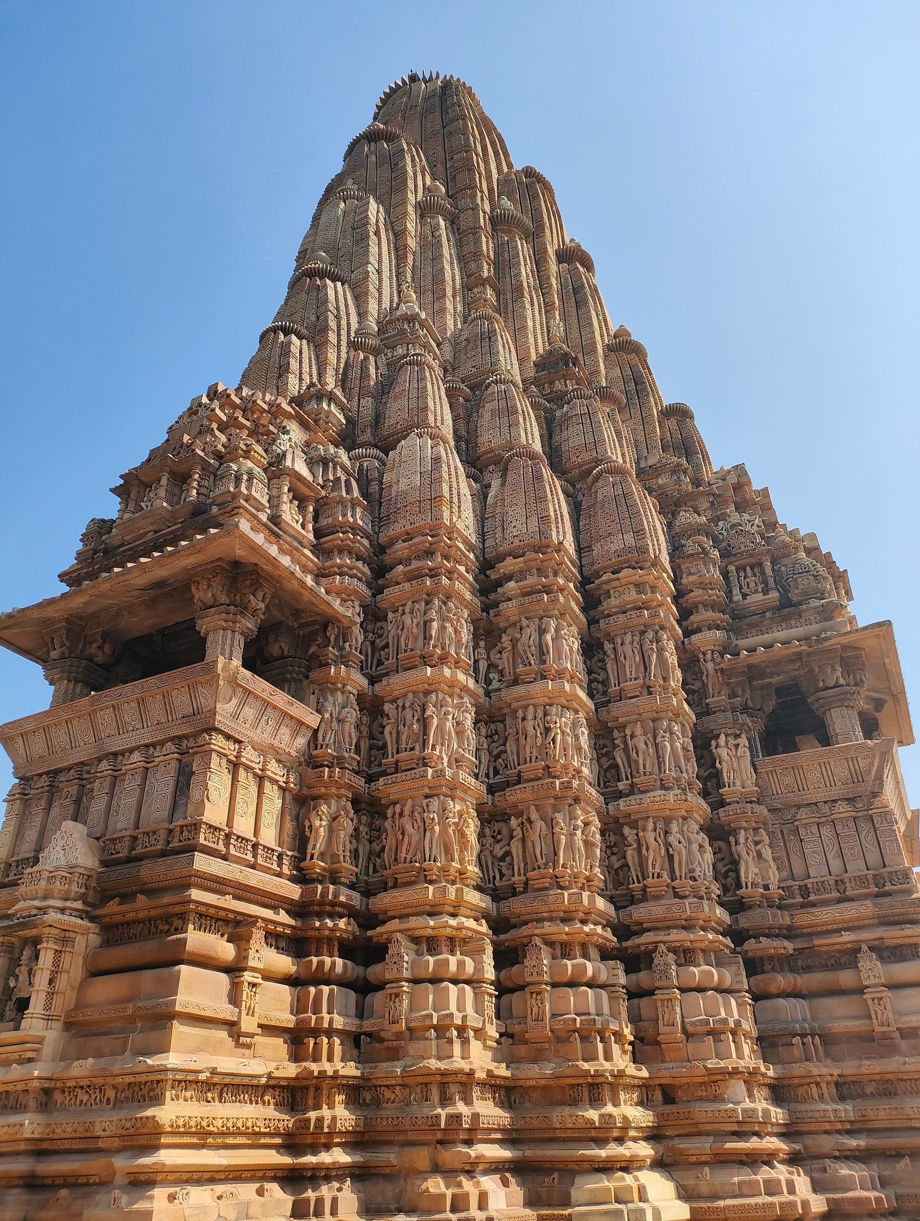 The tiered sandstone spire of a Khajuraho temple against a clear sky