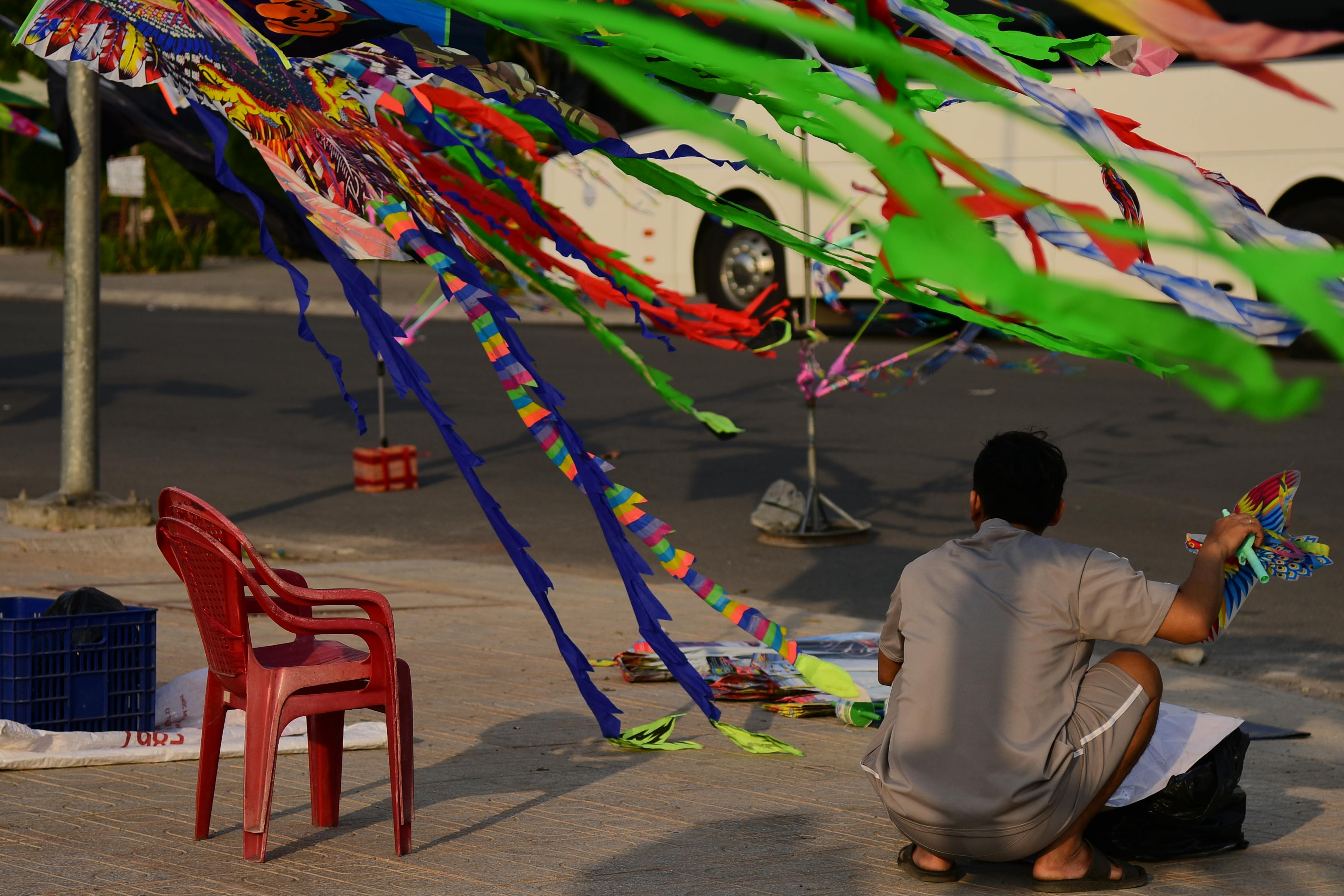 Gratuit Un vendeur dispose des cerfs-volants colorés dans une rue de la ville, en prévision des ventes. Photos