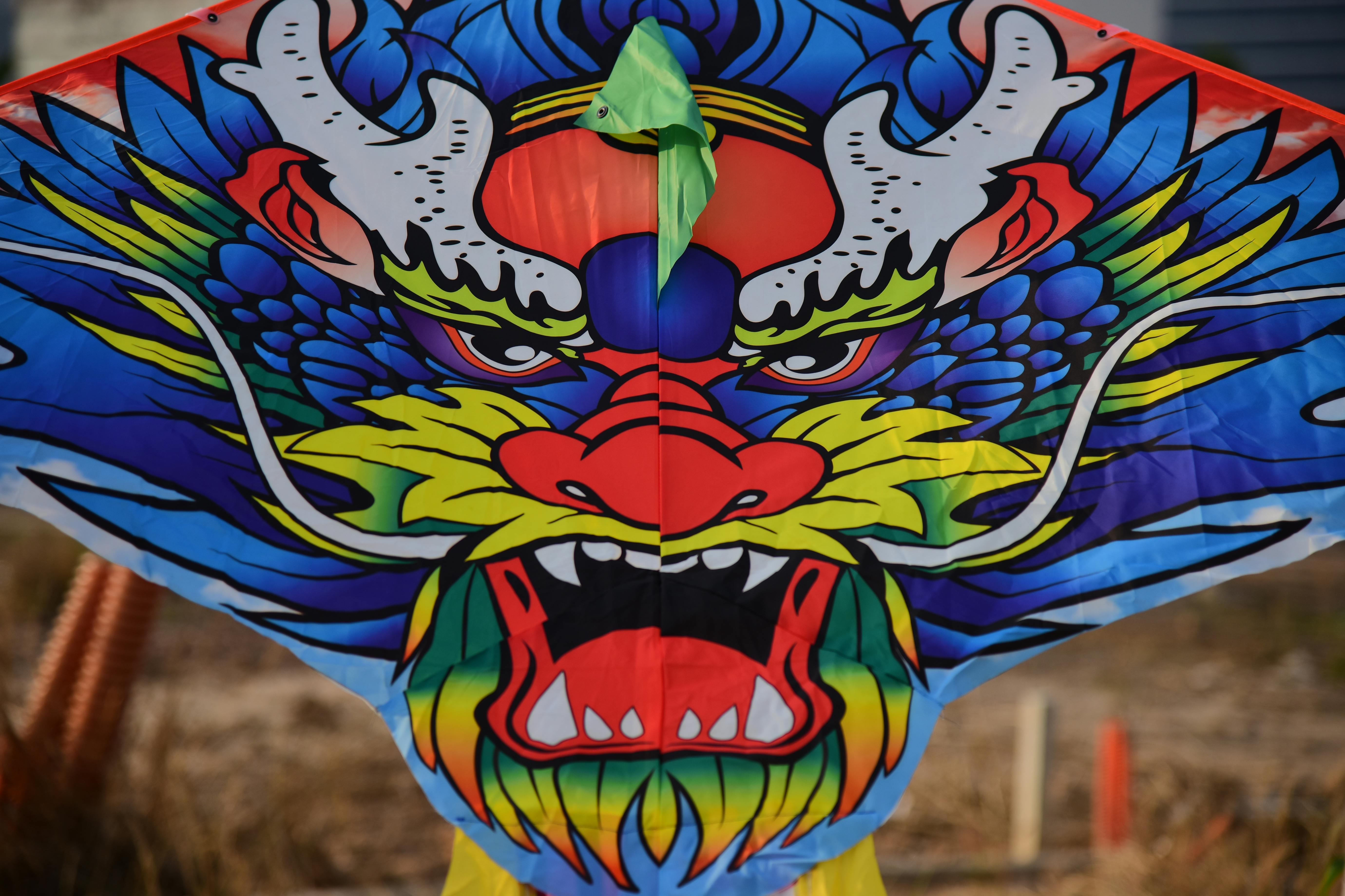 Free Vibrant dragon kite design with bold colors and fierce expression fluttering outdoors. Stock Photo