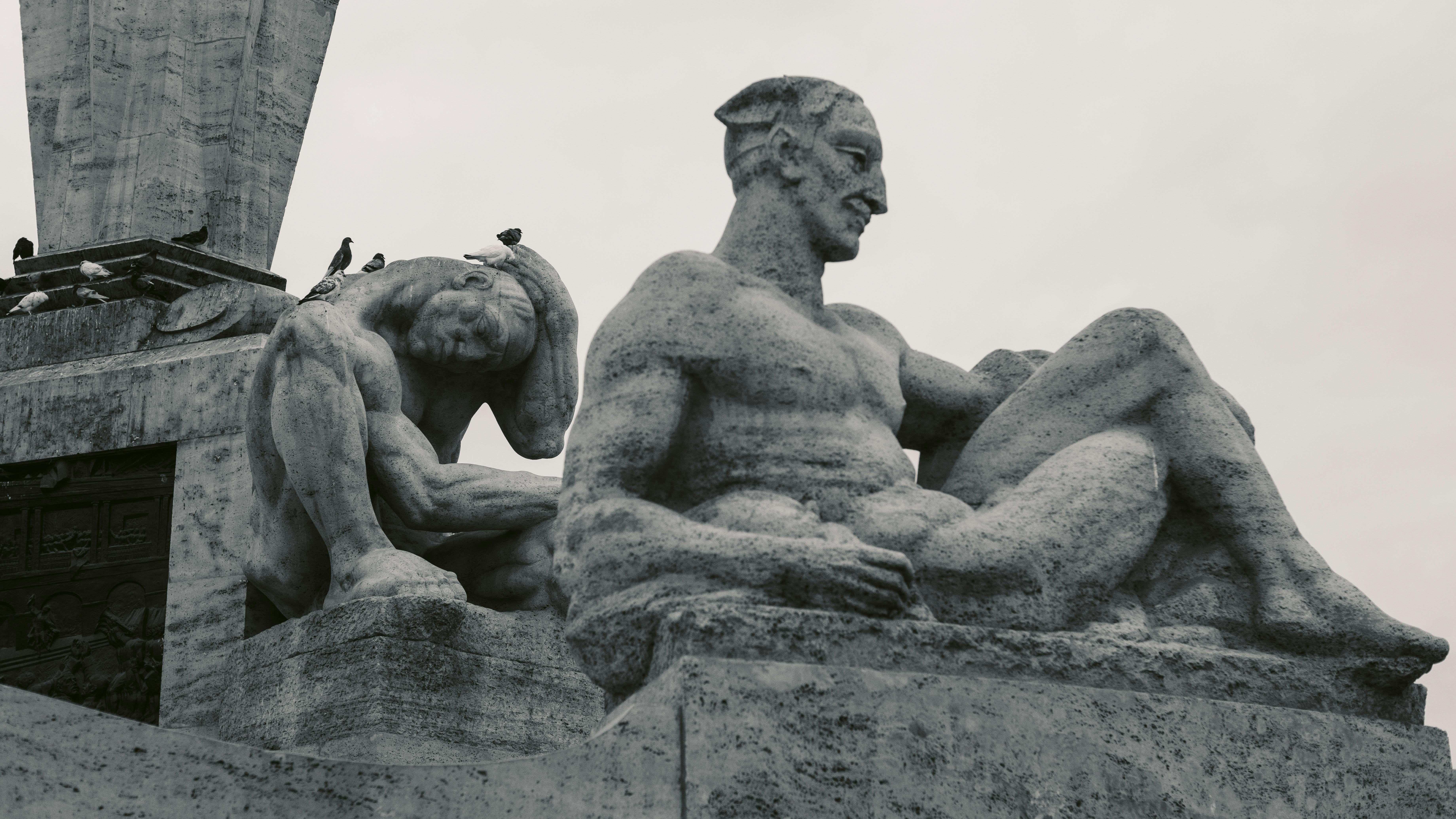 Безкоштовне Художній знімок великих кам'яних статуй з птахами, що сидять на монументальній споруді. стокове фото