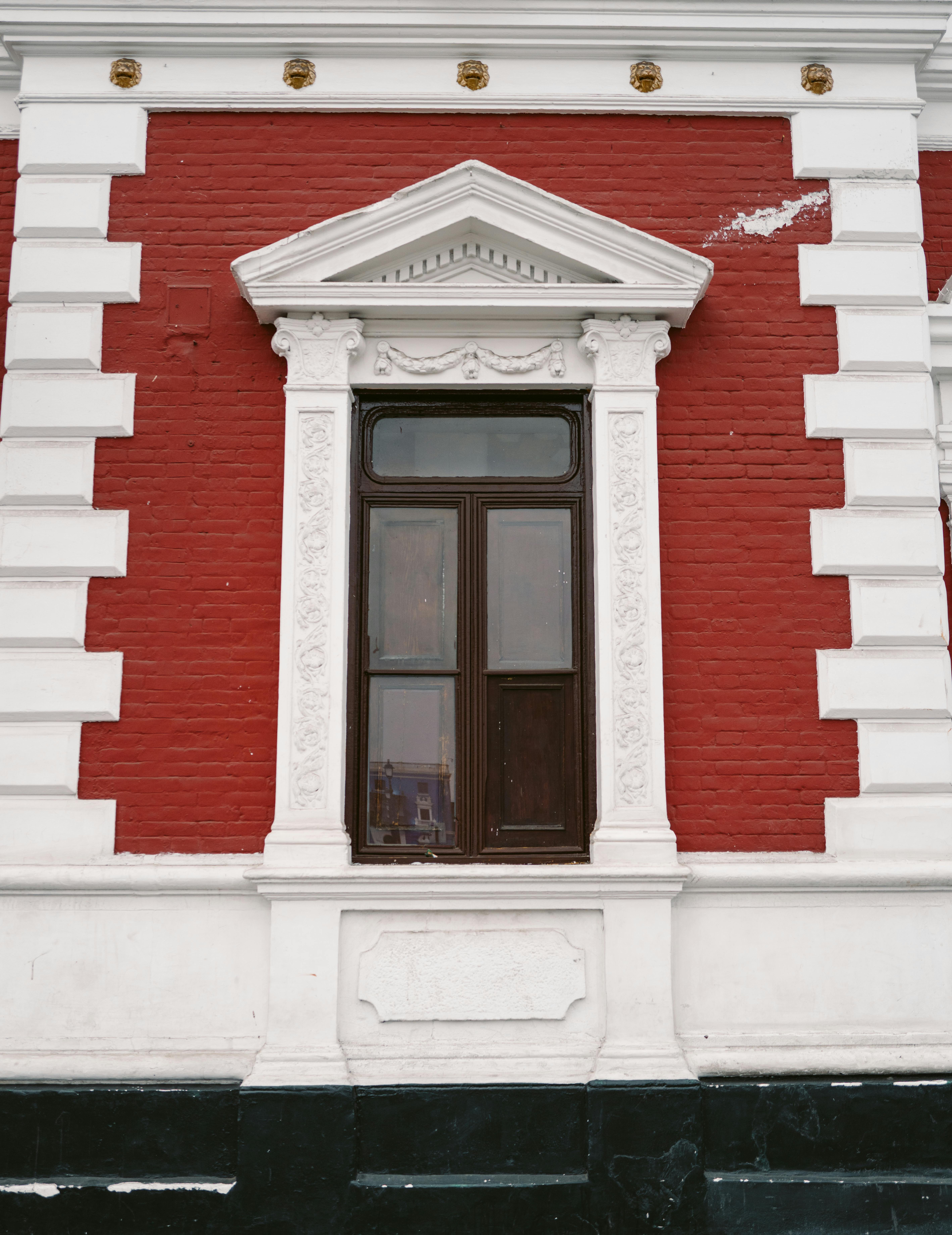 De franc Una vista detallada d'una finestra ornamentada en un edifici de maó vermell amb elements arquitectònics blancs. Foto d'estoc