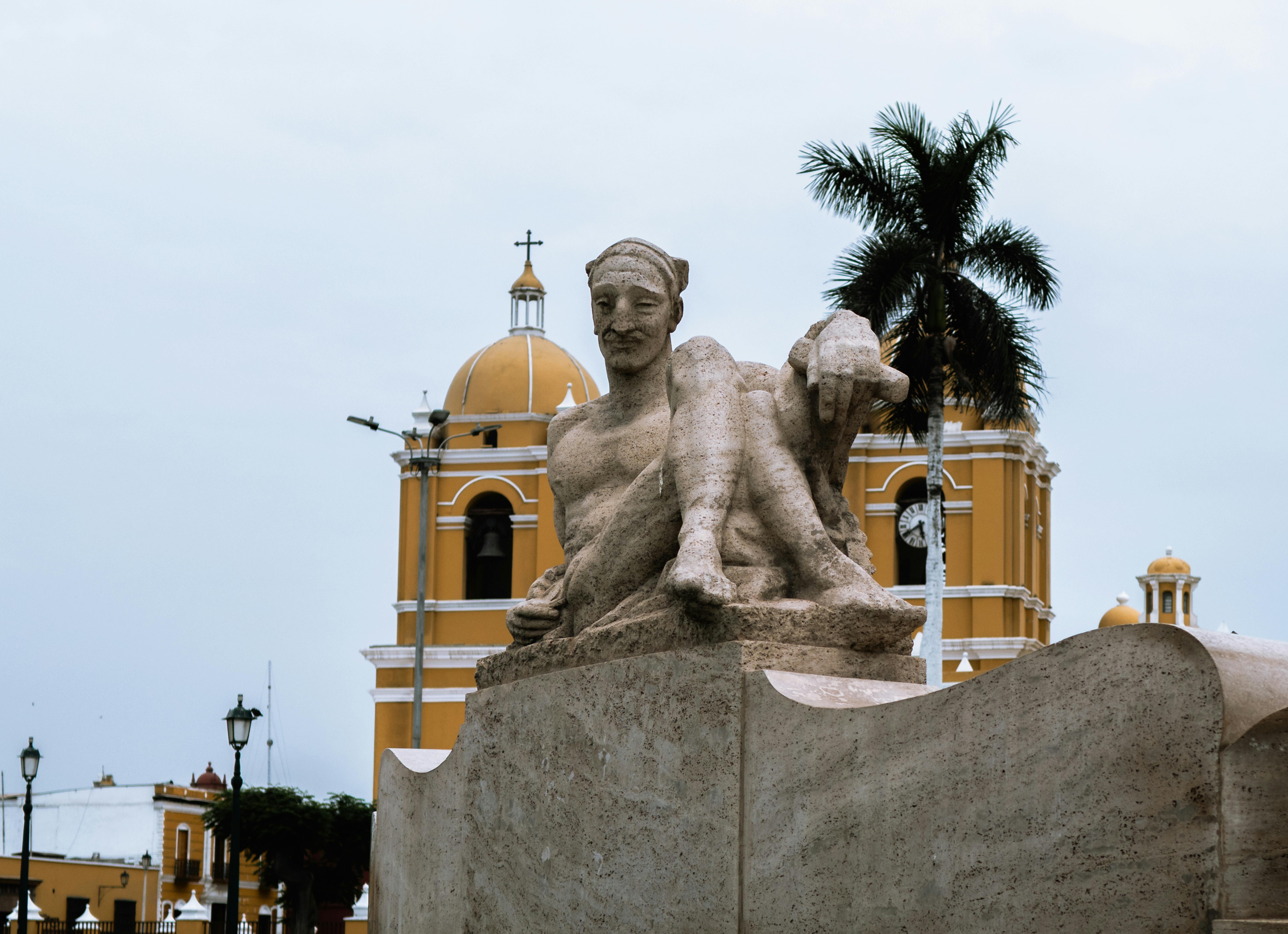 Gratis Plaza de Armas a Trujillo, in Perù, con la sua imponente scultura e l'architettura coloniale sotto un cielo nuvoloso. Foto a disposizione
