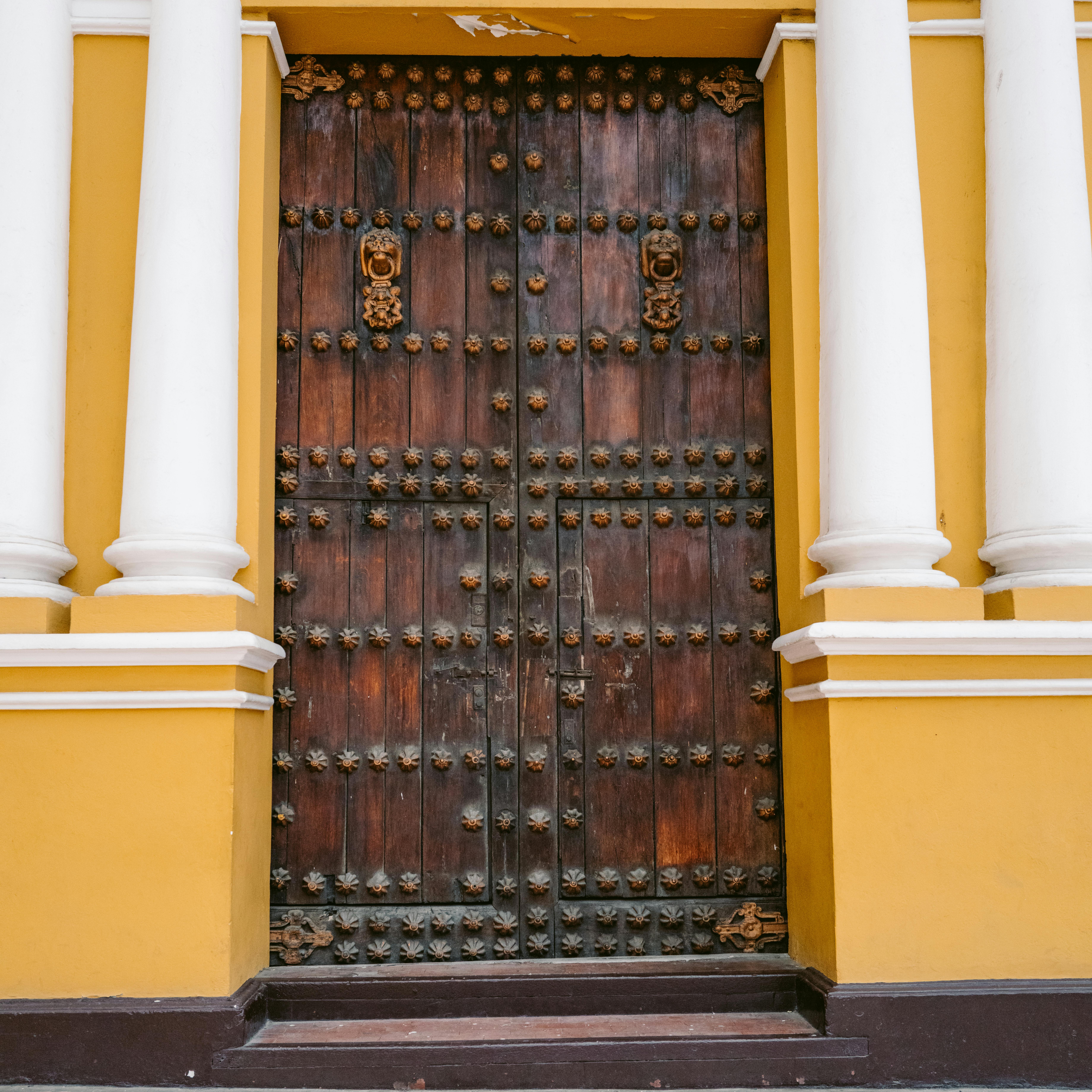 Gratuit O ușă din lemn cu design complex, încadrată de coloane galbene vibrante în Trujillo, Peru. Fotografie de stoc