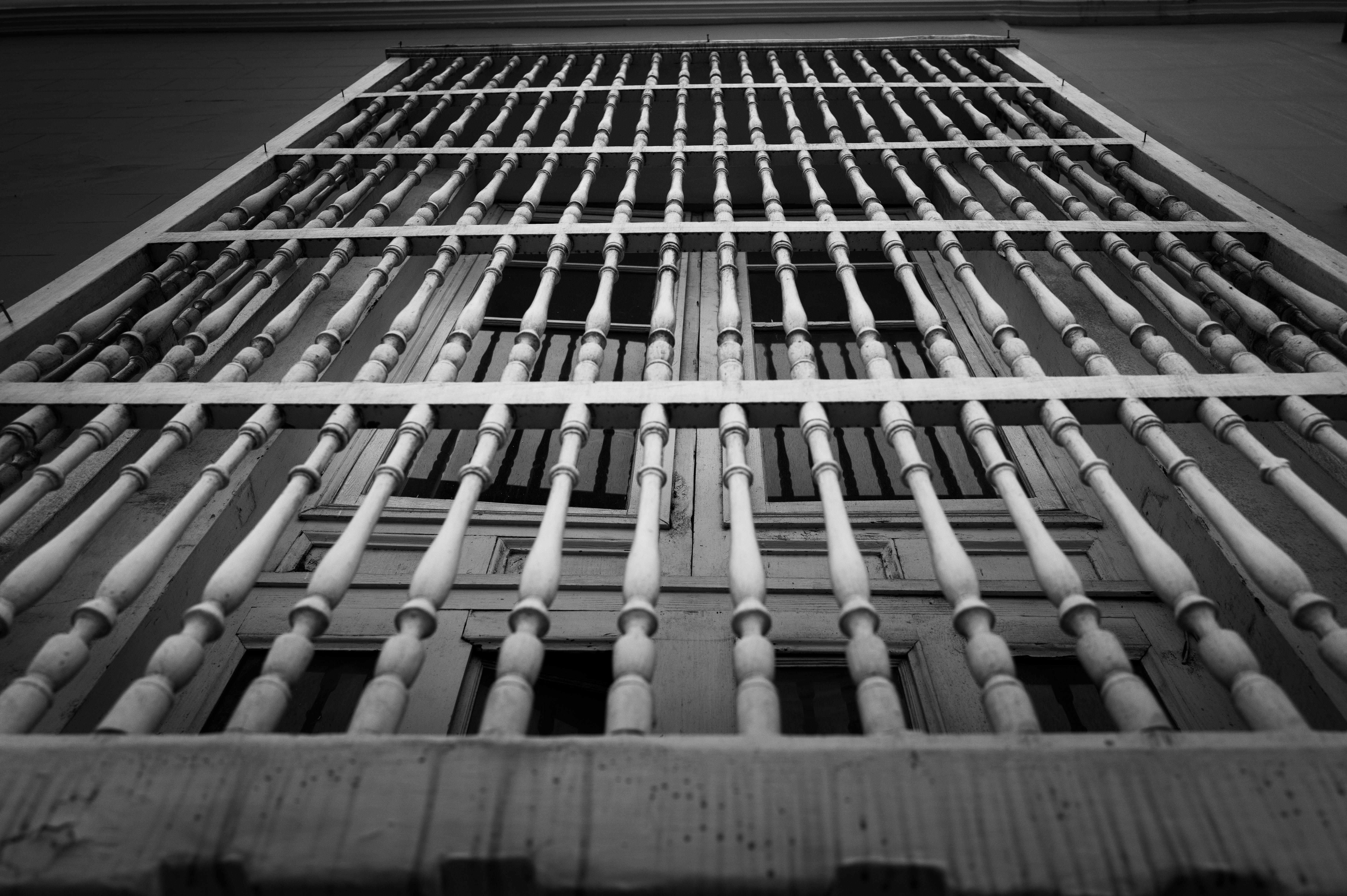 Kostenlos Schwarz-Weiß-Aufnahme von Fenstergittern im Kolonialstil, aufgenommen von unten in Trujillo, Peru. Stock-Foto